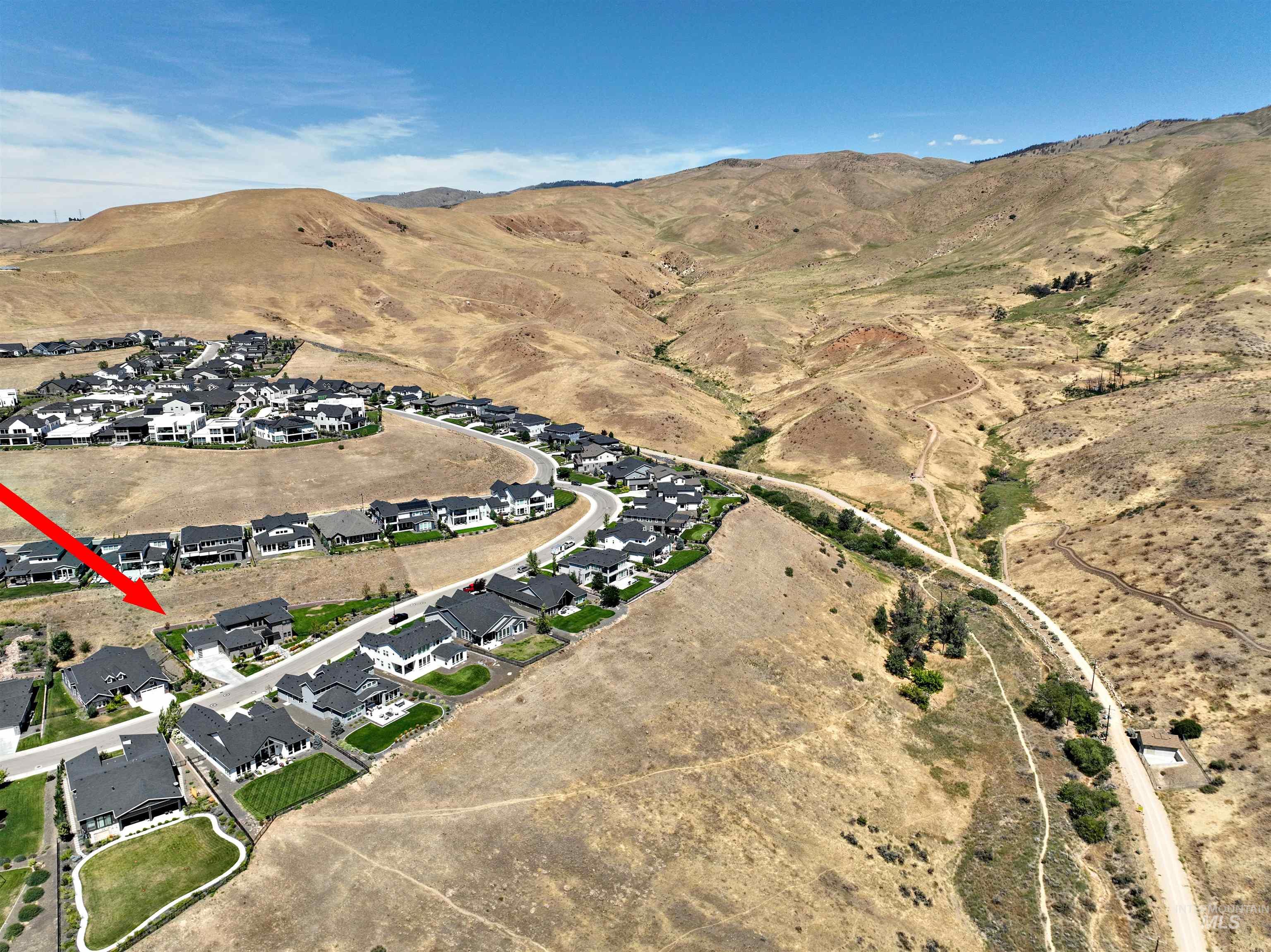 Aerial view of property and surrounding area featuring a mountainous background and nearby suburban area