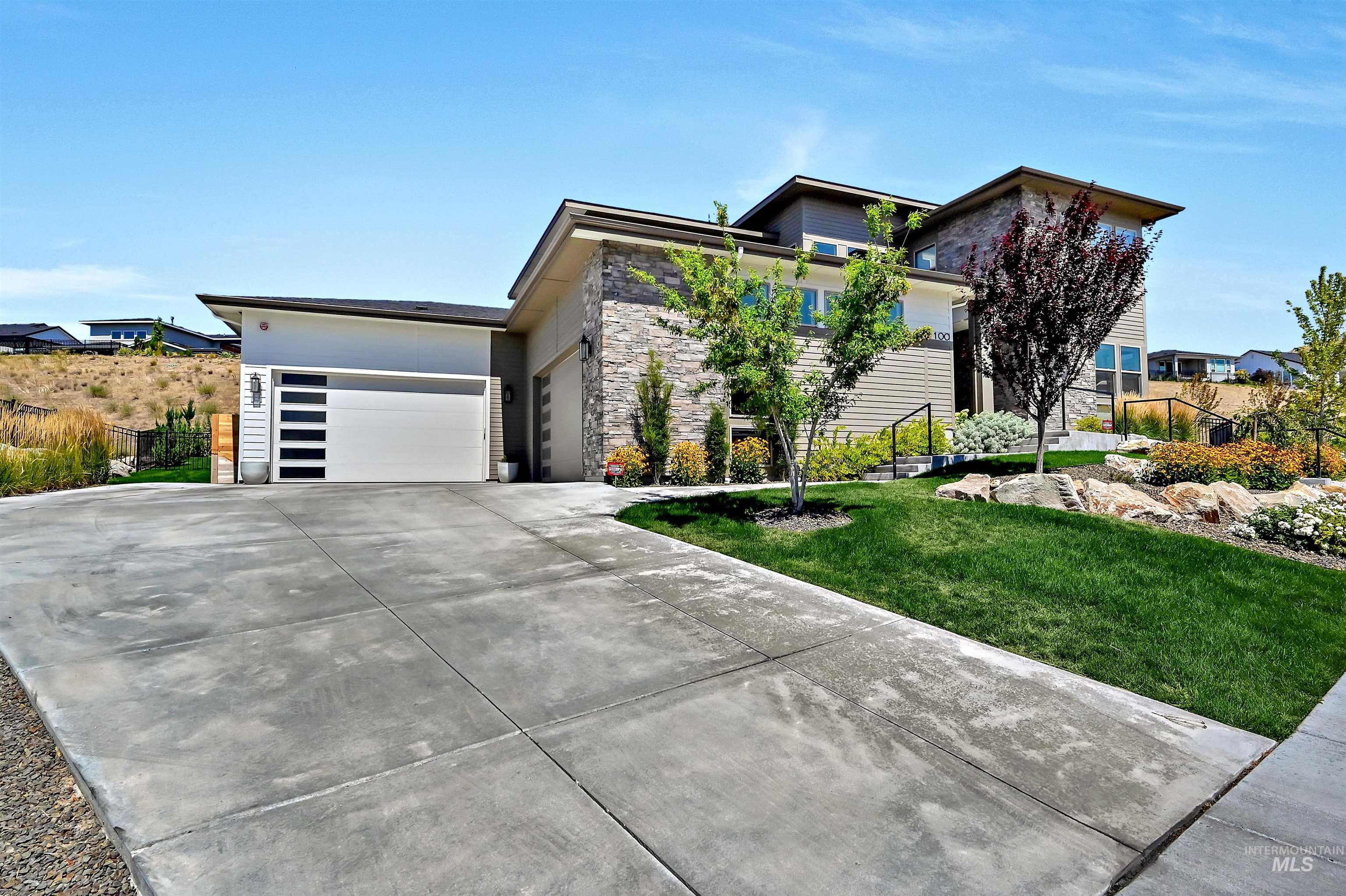 View of front of property featuring a garage, stone siding, and driveway