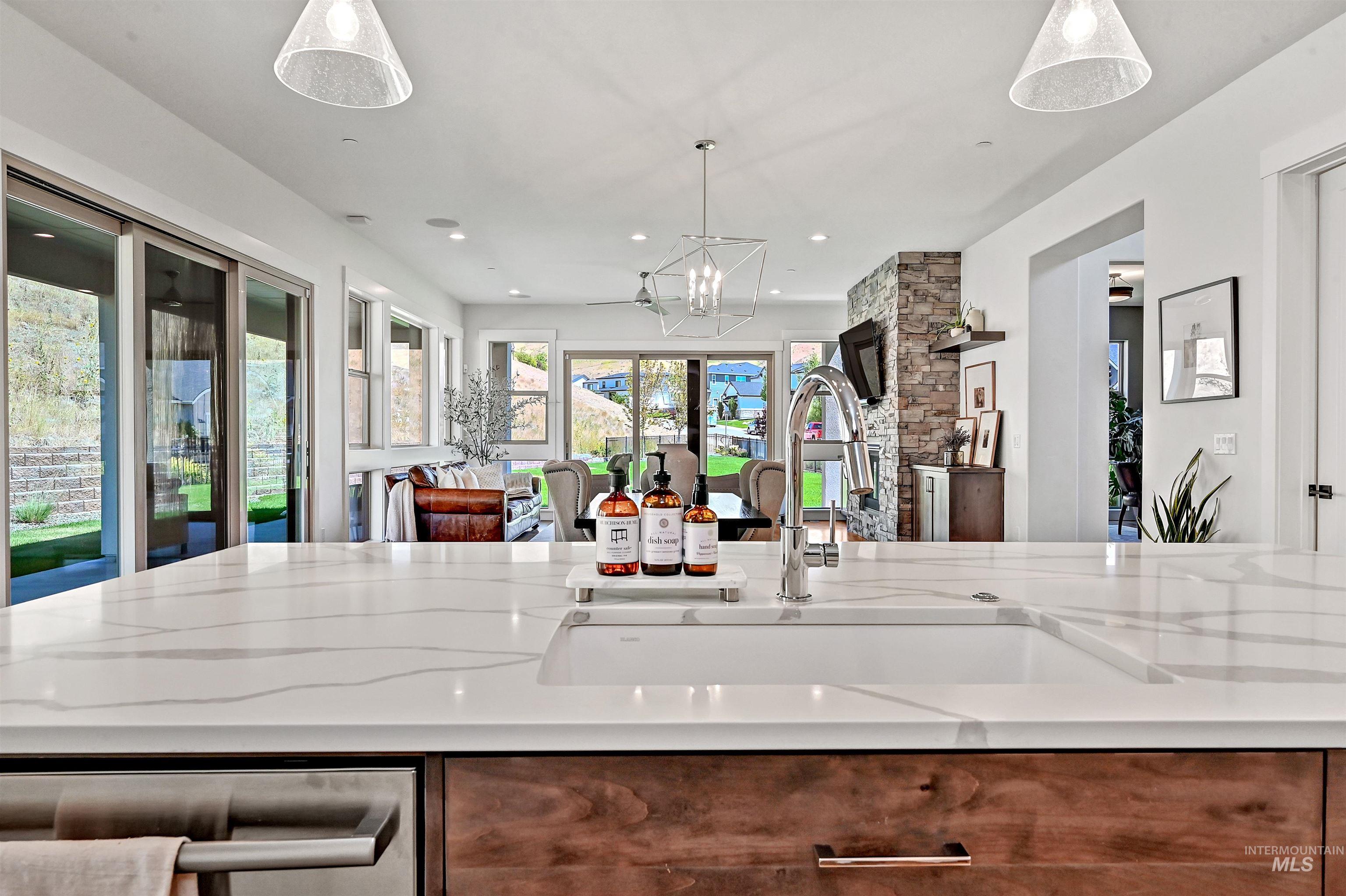 Kitchen featuring light stone countertops, decorative light fixtures, recessed lighting, open floor plan, and brown cabinets