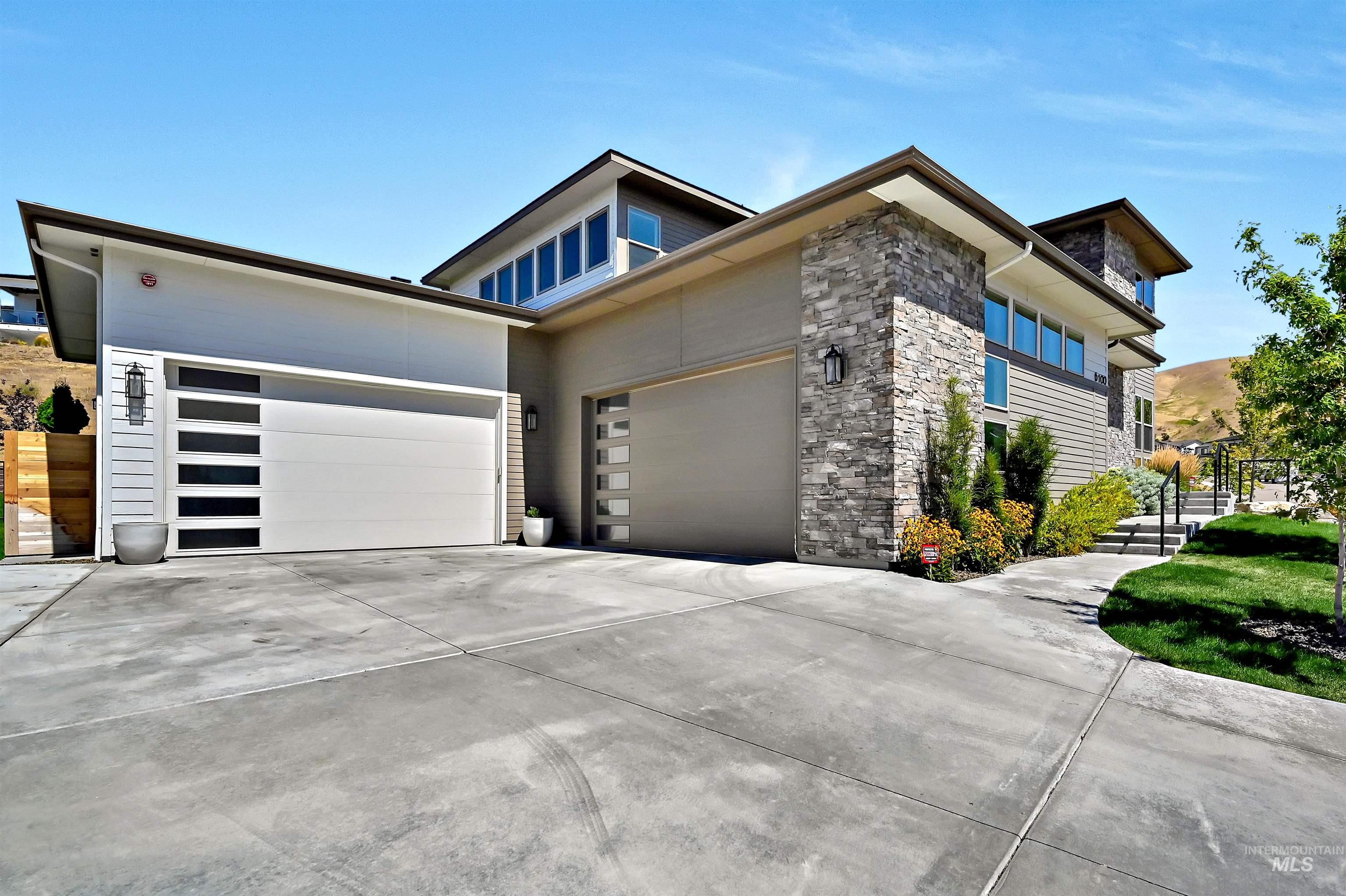 Modern home featuring stone siding, driveway, and an attached garage