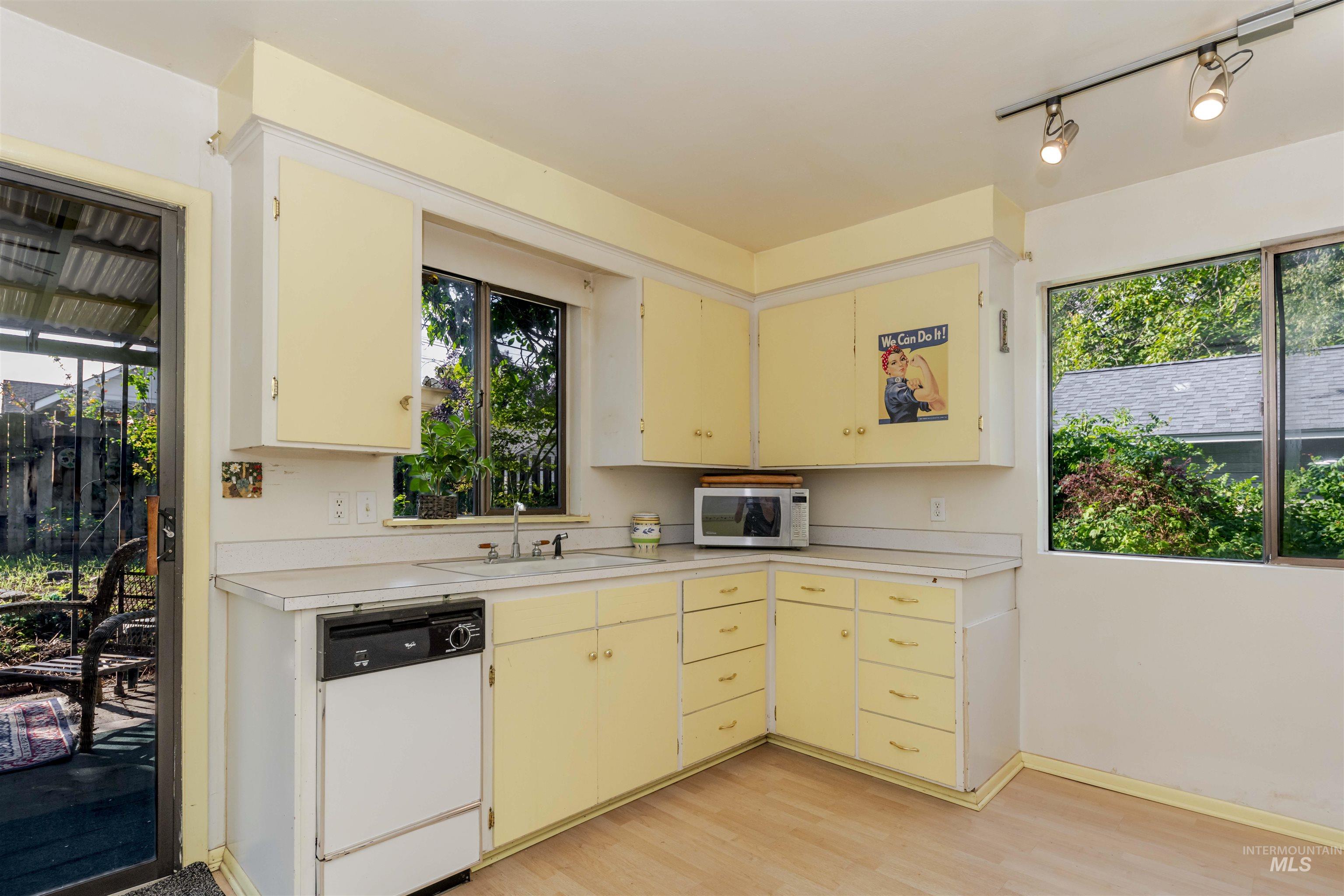 Kitchen with white appliances, light countertops, light wood-style flooring, and healthy amount of natural light