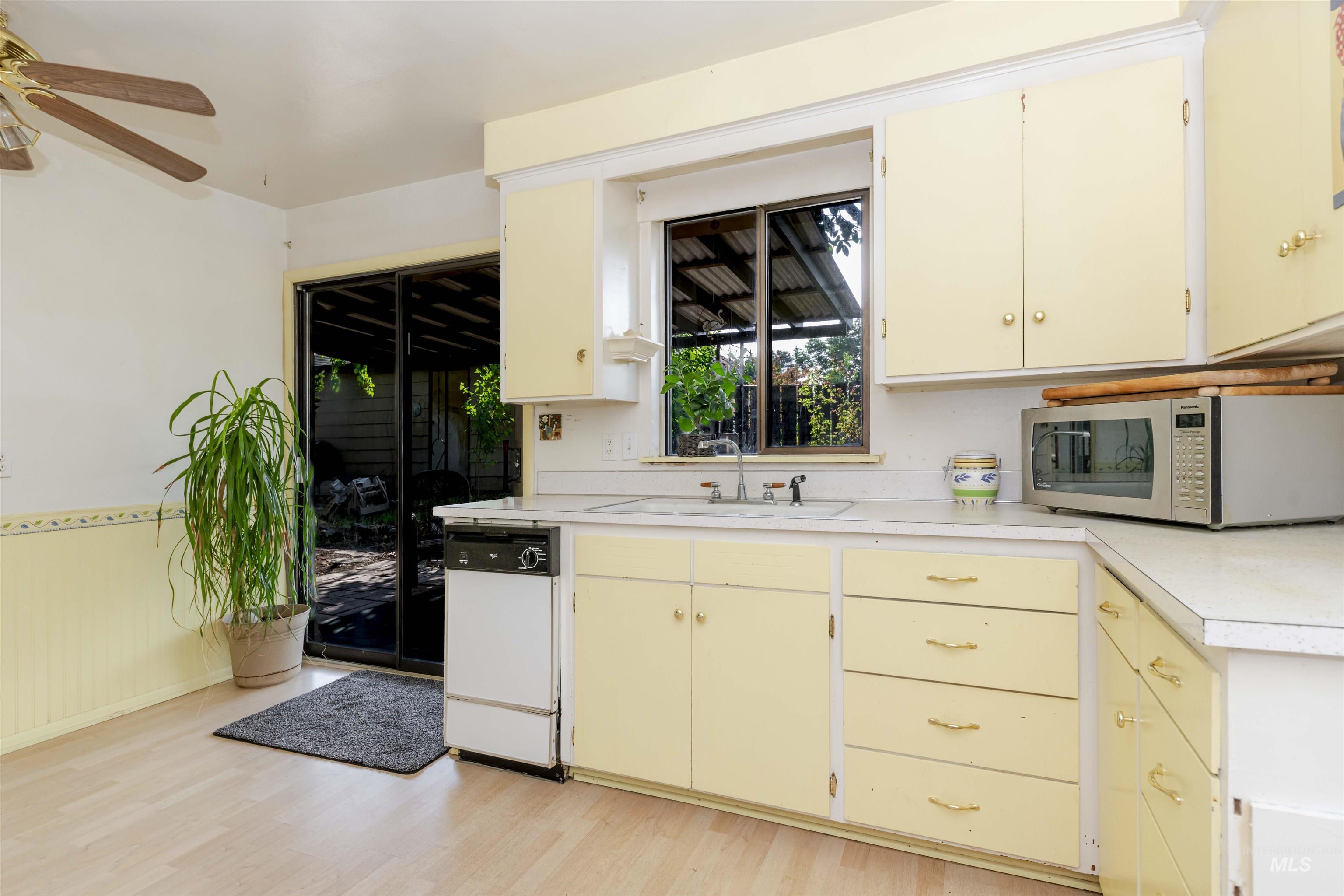 Kitchen with light countertops, light wood-style flooring, dishwasher