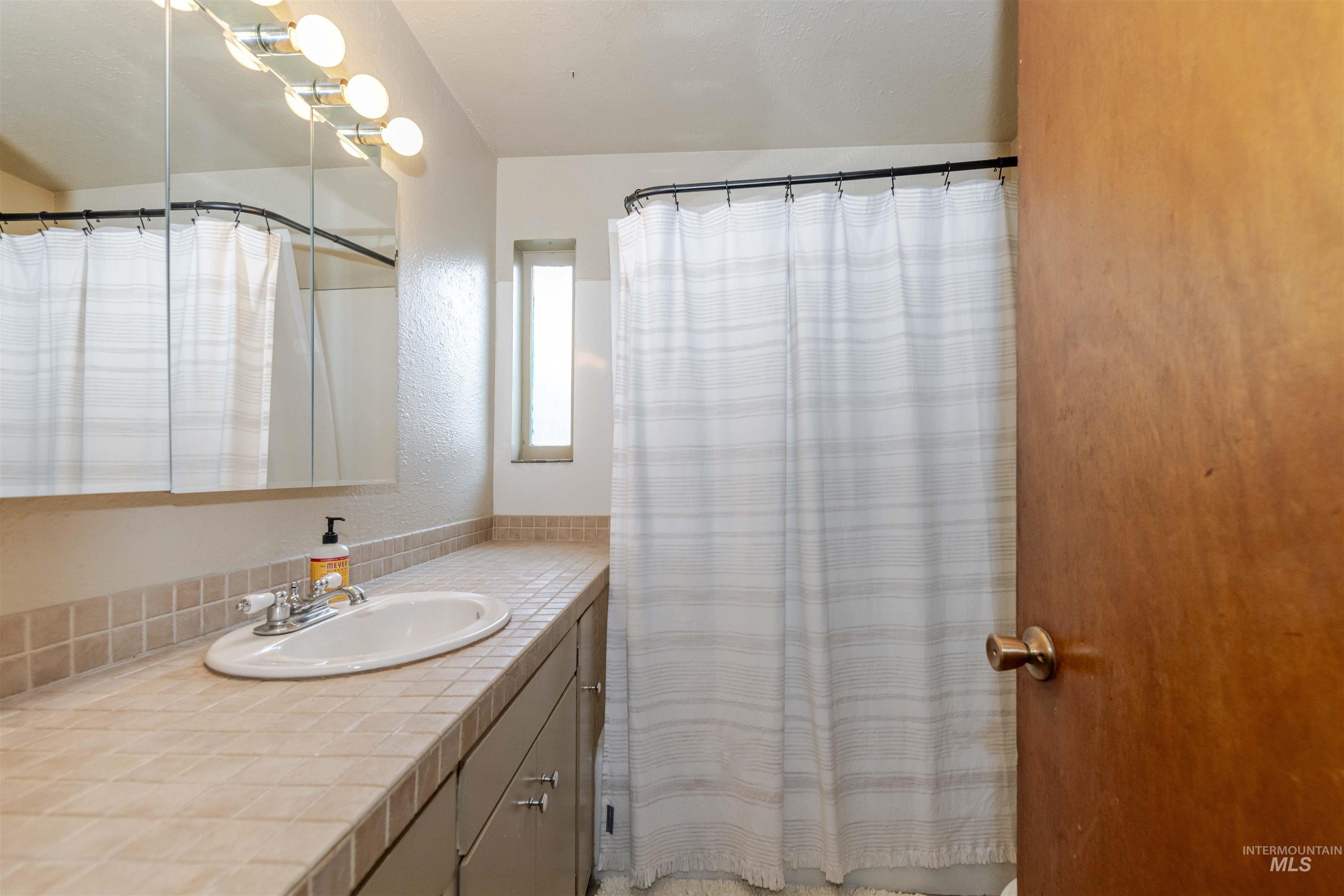 Full bath featuring tiled vanity and tub/shower