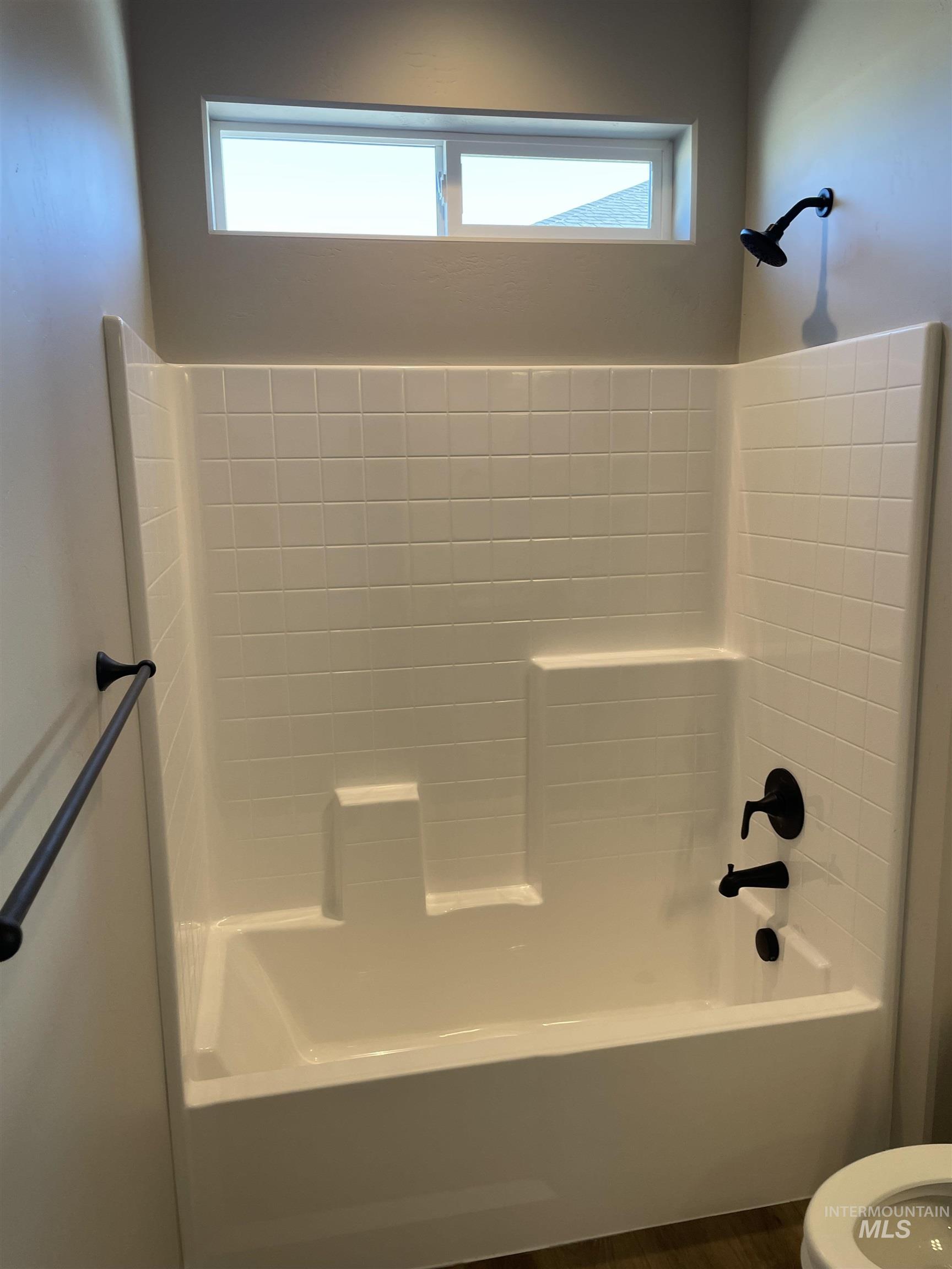 Bathroom with shower / washtub combination and dark wood finished floors