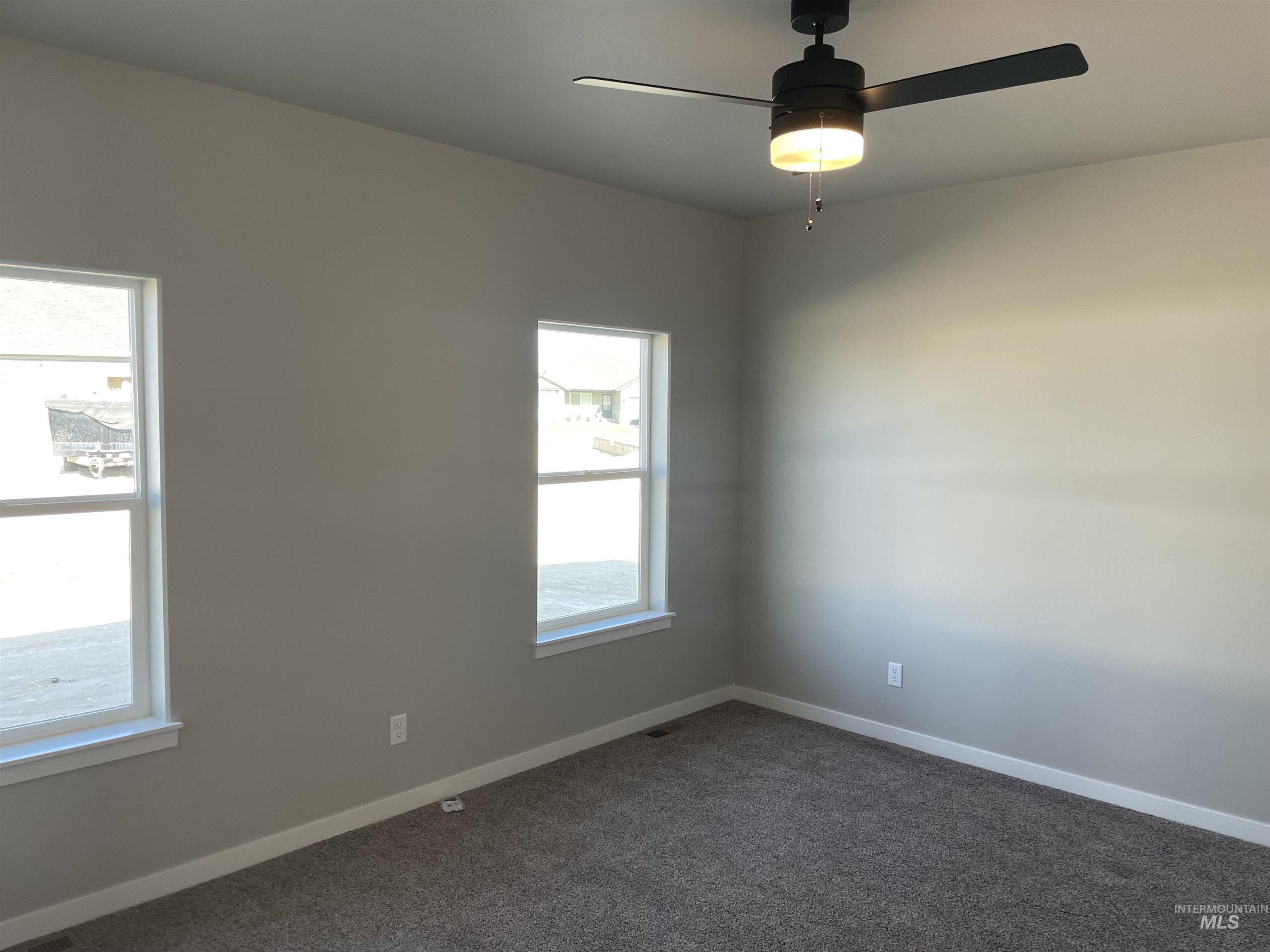 Carpeted empty room featuring baseboards and ceiling fan