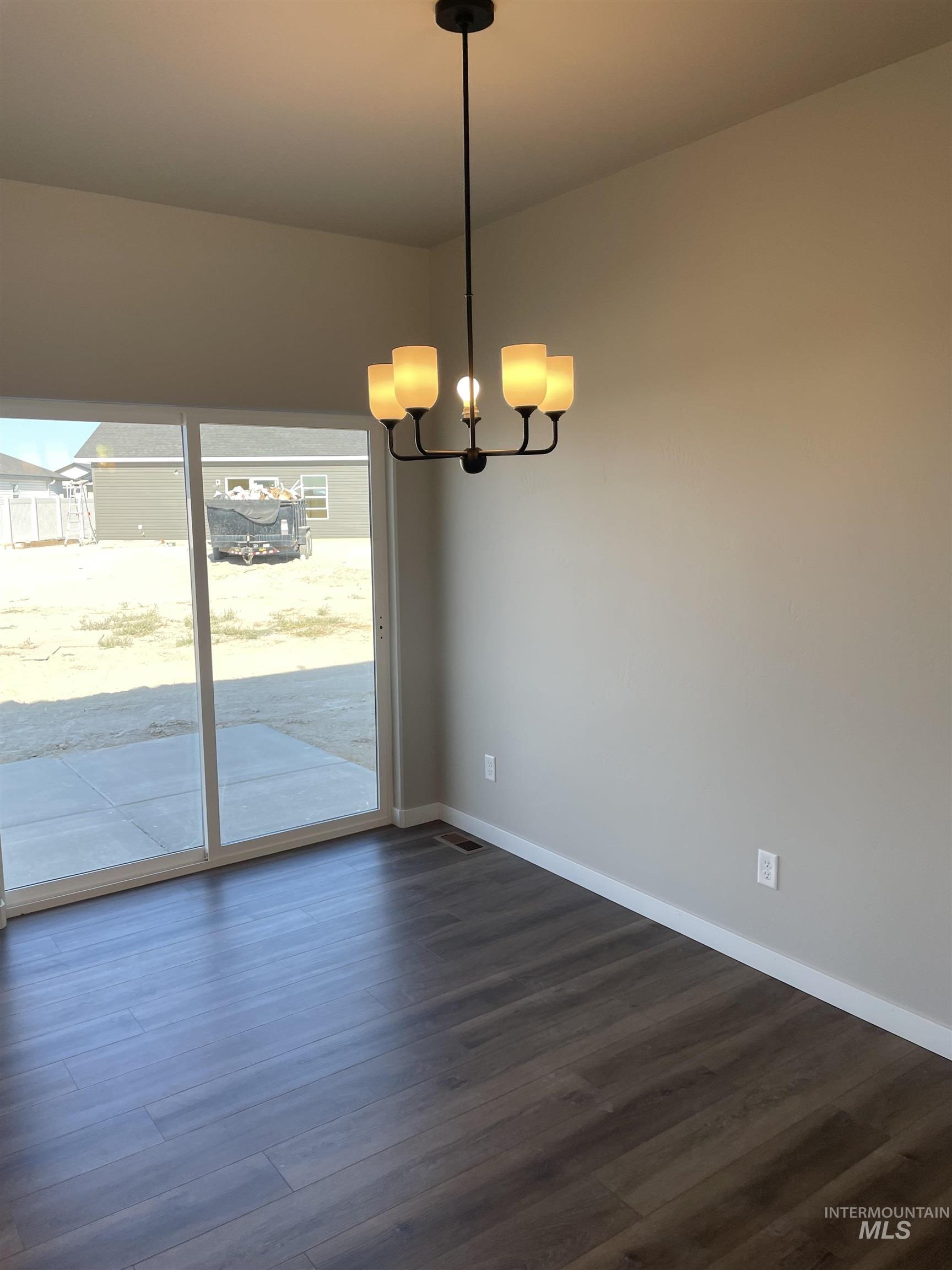 Unfurnished dining area with dark wood-type flooring and a chandelier