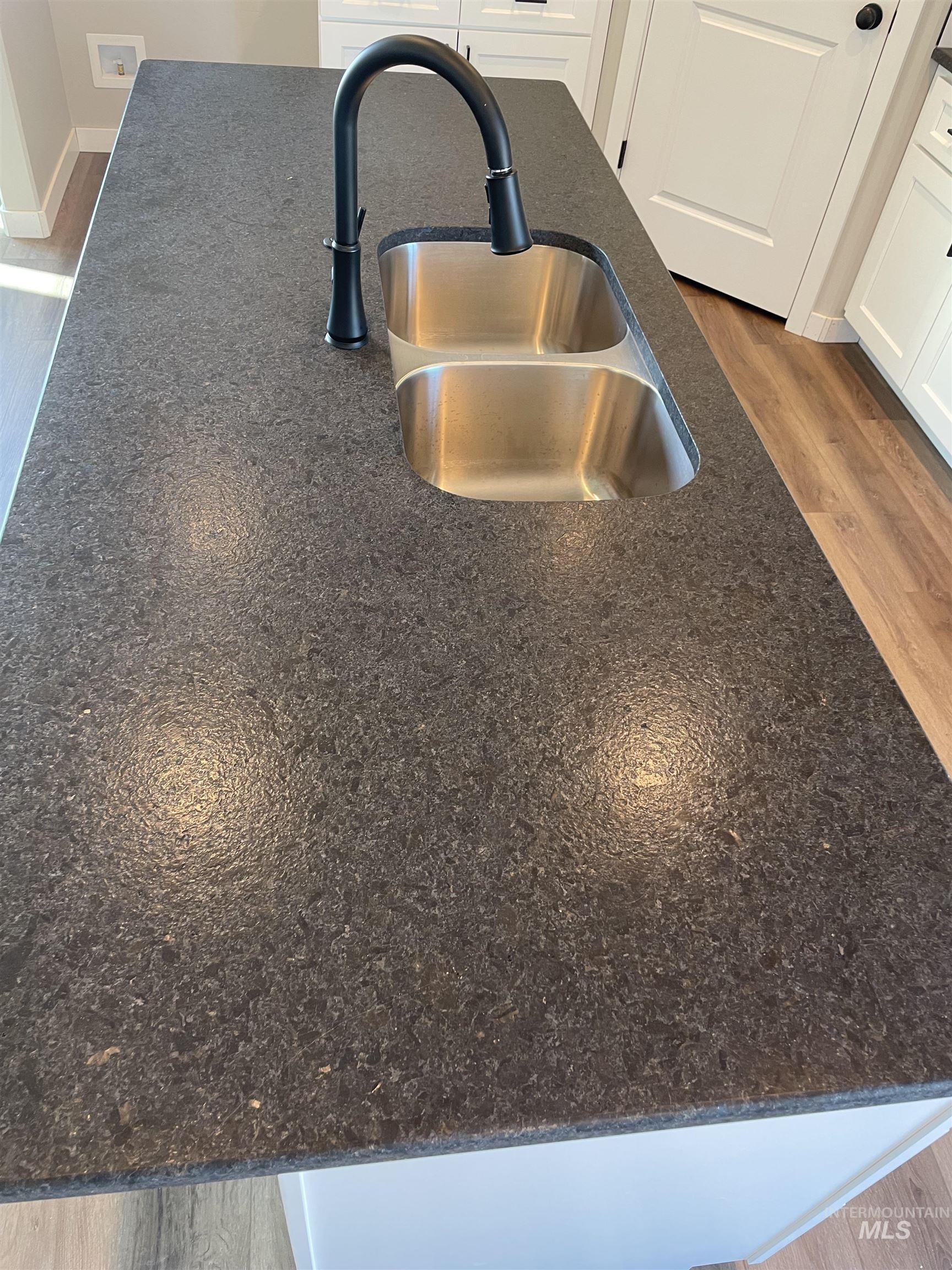 Kitchen view of dark wood-style flooring and dark stone counters