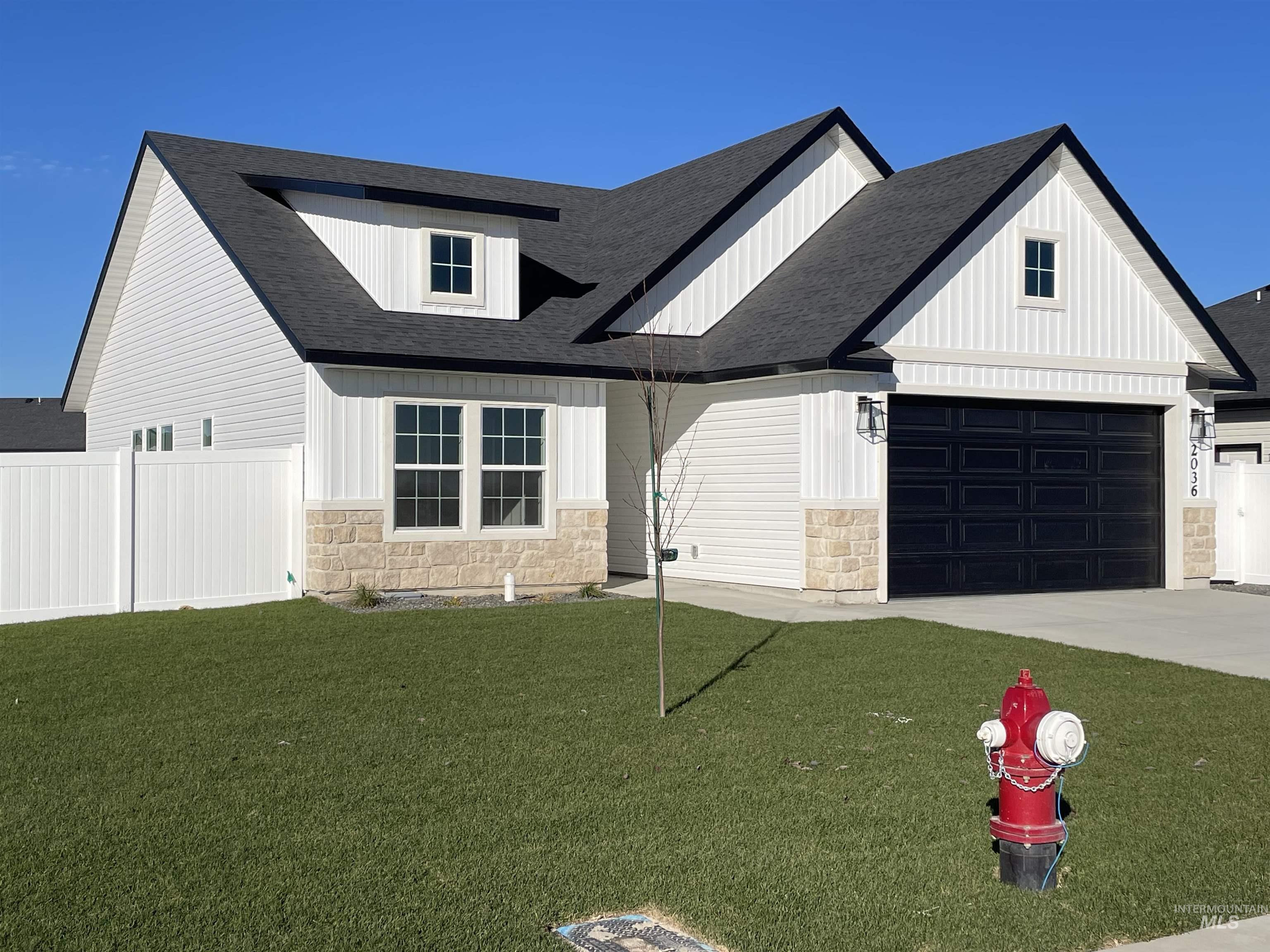 Modern farmhouse with stone siding, a shingled roof, and concrete driveway