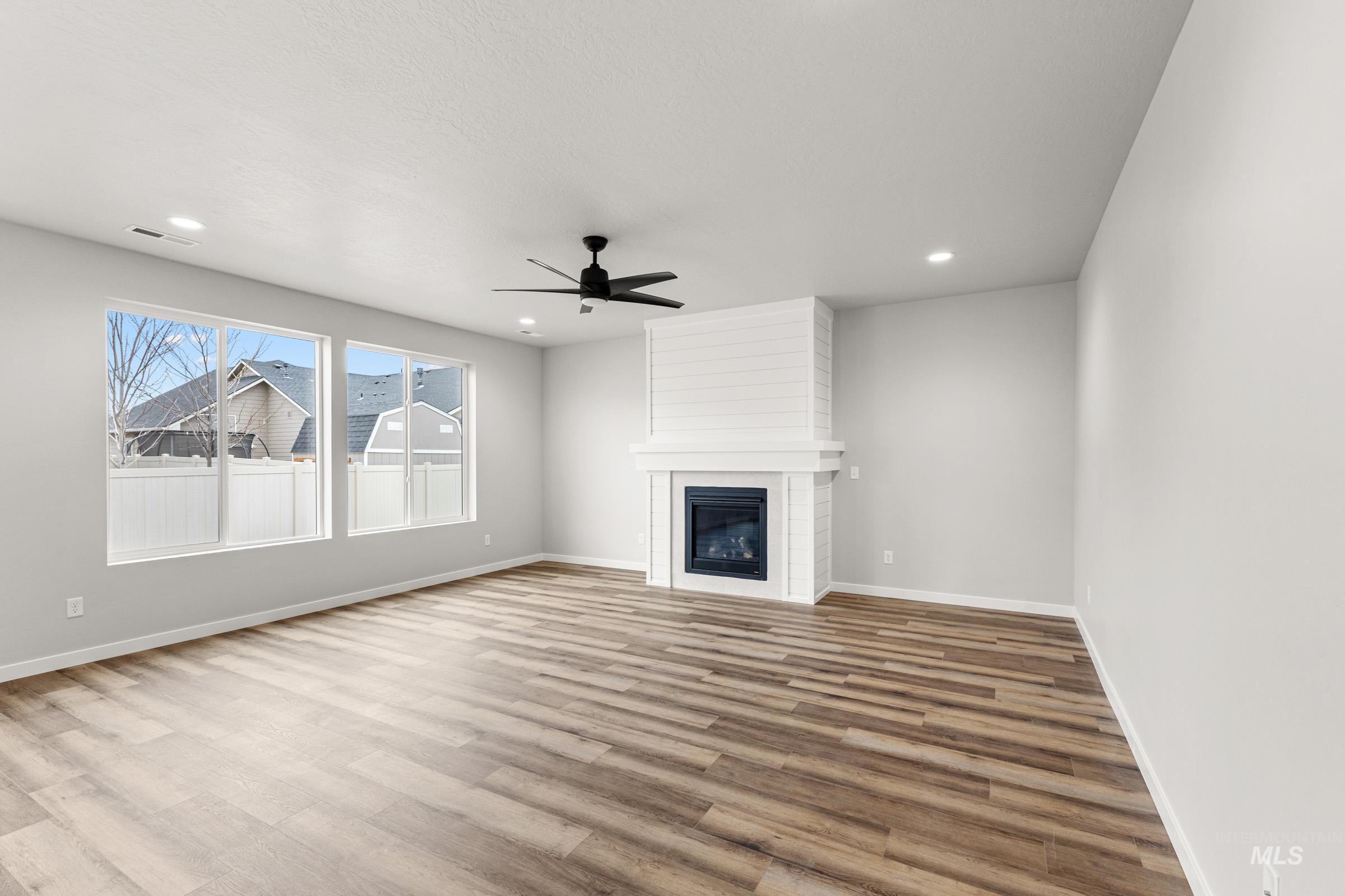 Unfurnished living room featuring a ceiling fan, light wood-type flooring, a large fireplace, and recessed lighting