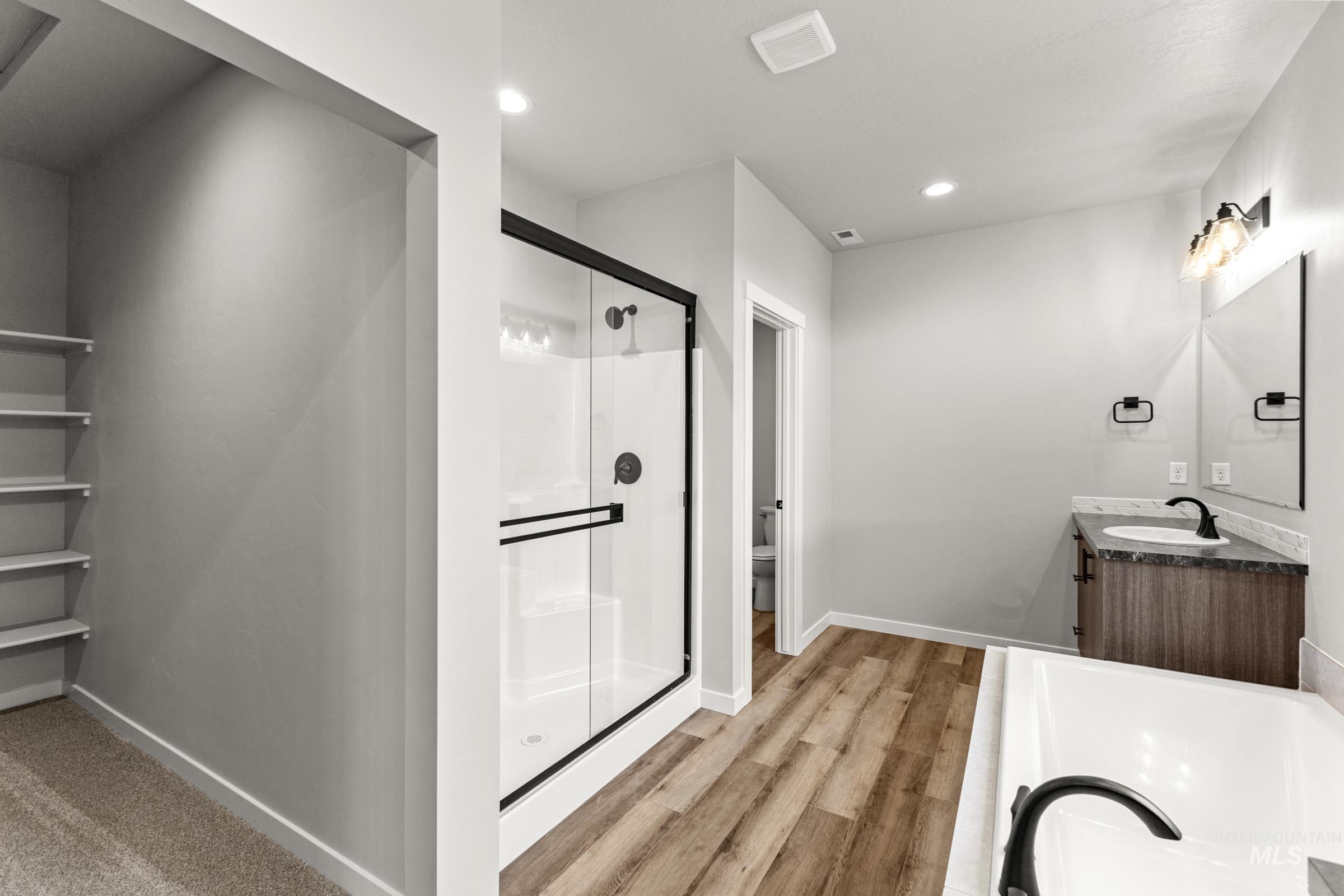 Full bathroom with a garden tub, vanity, a shower stall, light wood-style flooring, and recessed lighting