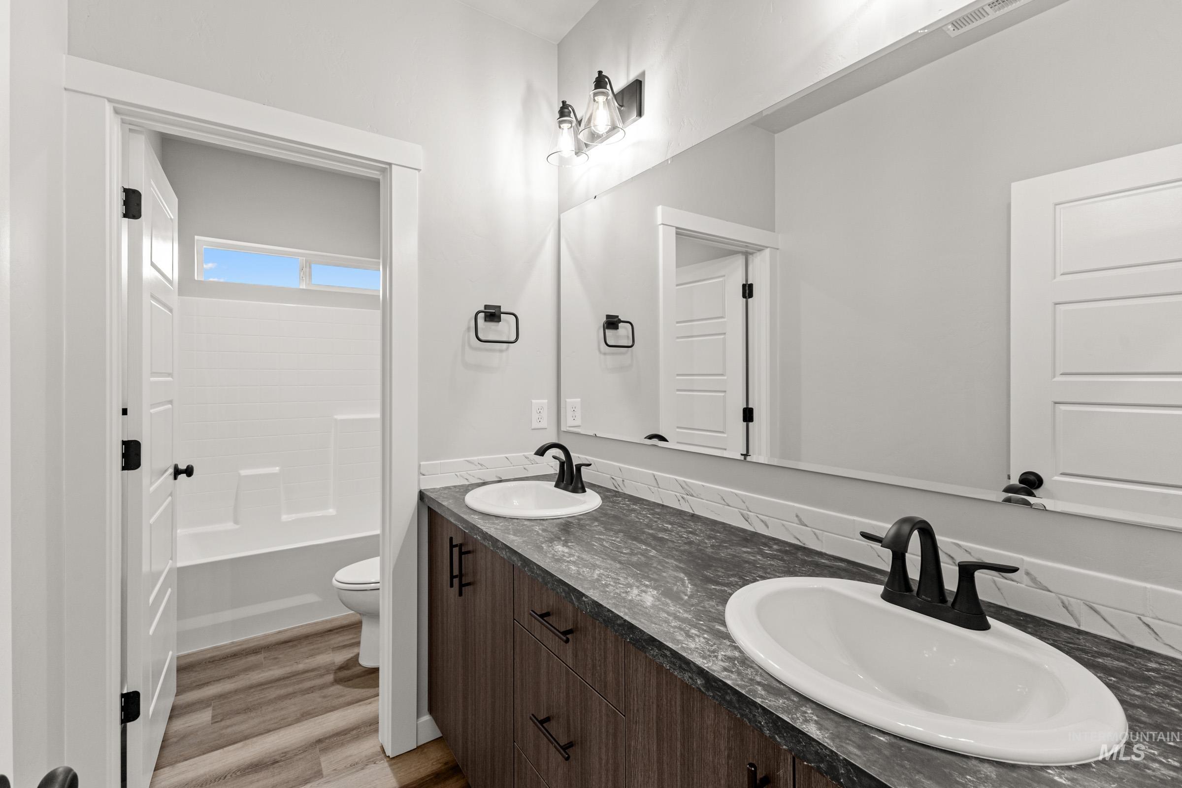 Bathroom featuring double vanity, light wood-type flooring, and tub / shower combination