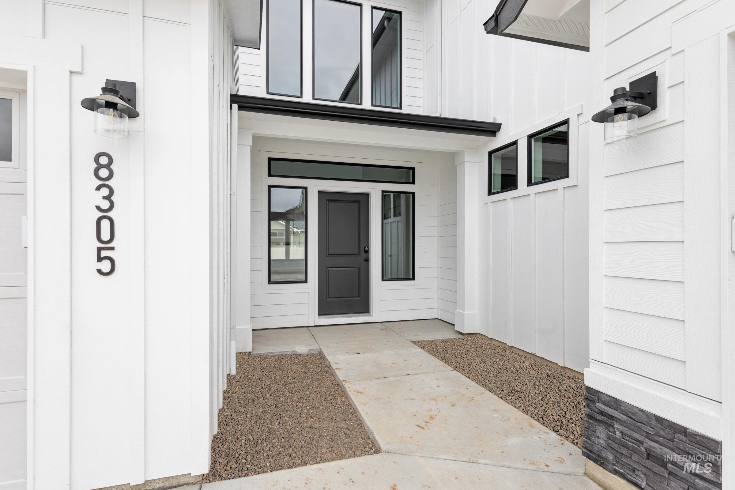 View of exterior entry with board and batten siding and a porch