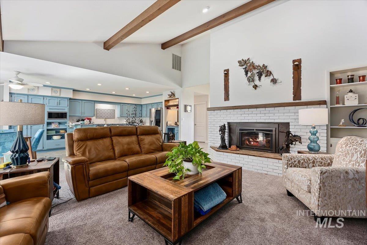 Carpeted living room featuring recessed lighting, a brick fireplace, vaulted ceiling, and ceiling fan