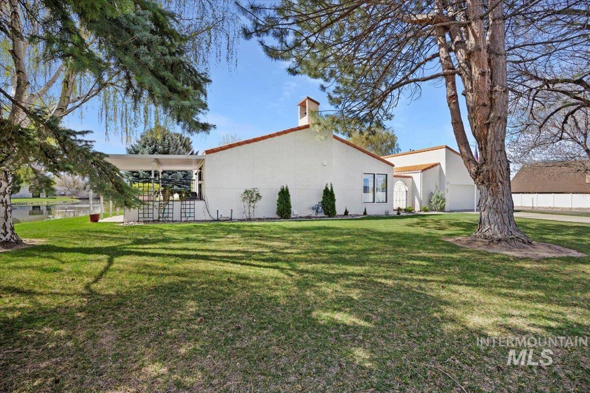 View of property exterior featuring a lawn, stucco siding, a chimney, and a garage