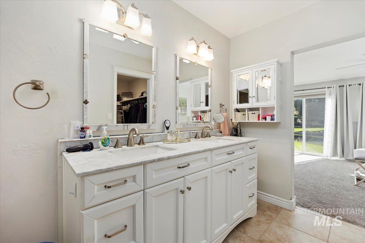 Full bath with double vanity, light carpet, and light tile patterned flooring