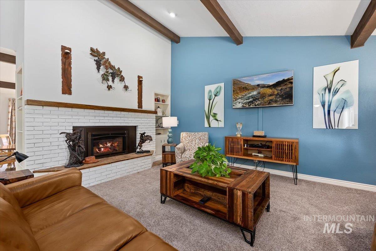 Carpeted living area featuring a fireplace and beamed ceiling