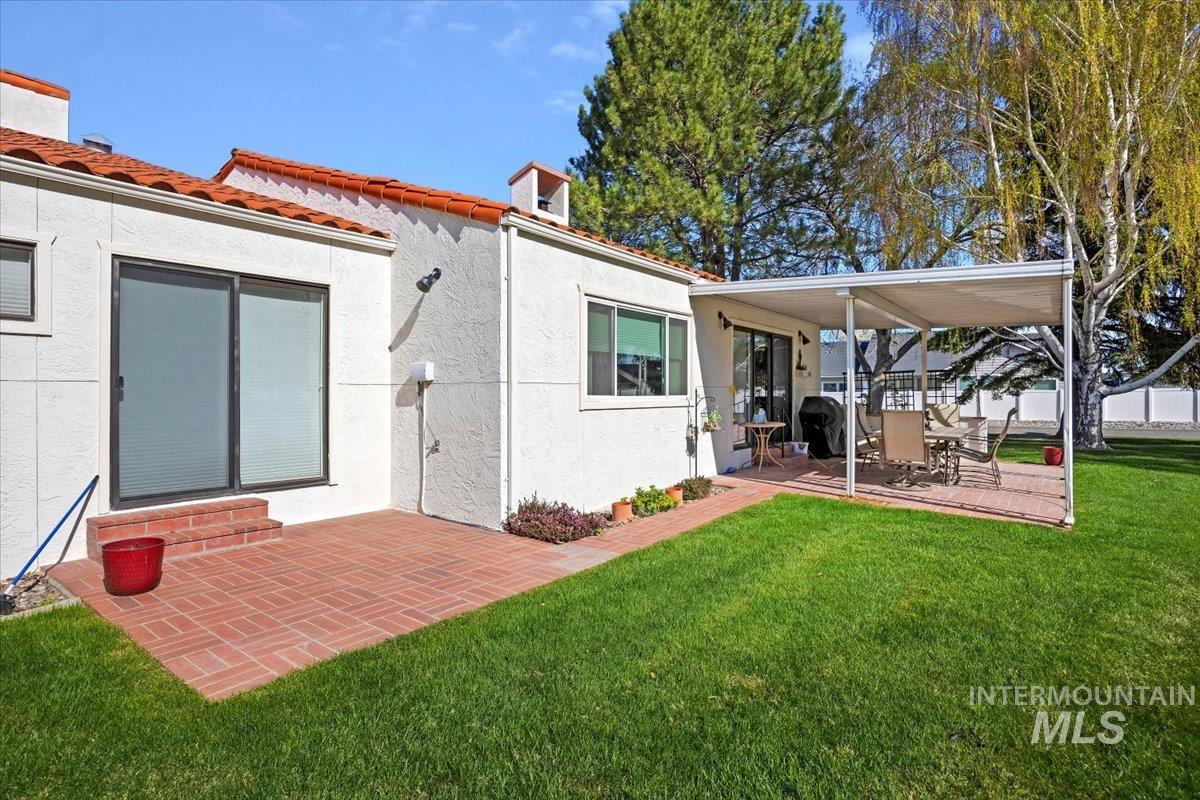 Back of house with stucco siding, a tile roof, a patio, and a deck