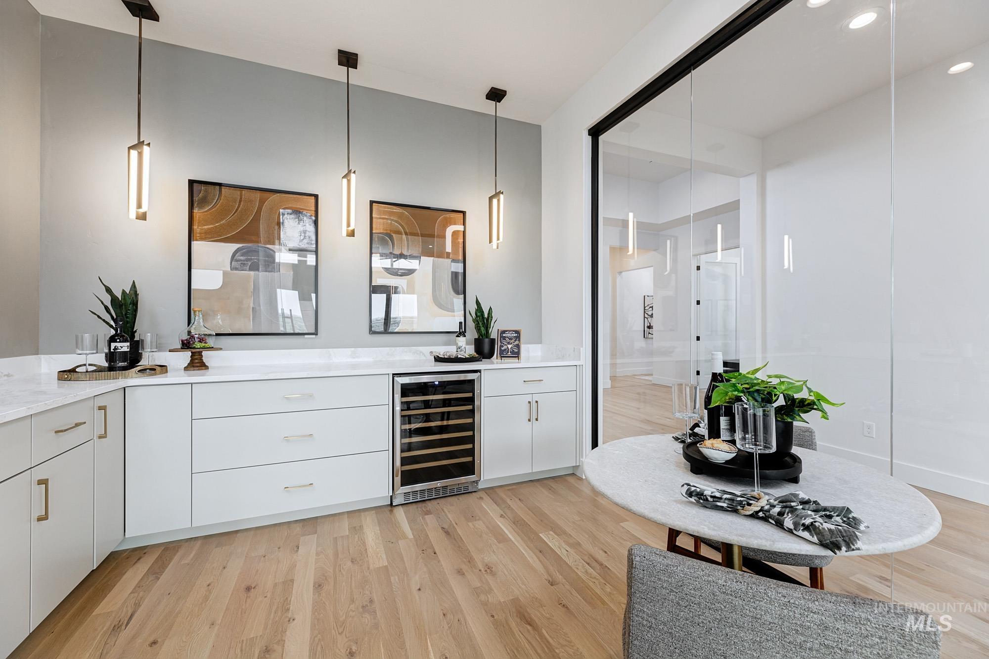 Built-in bar area featuring white cabinetry, light-toned countertops, a wine refrigerator, and wood-finish flooring