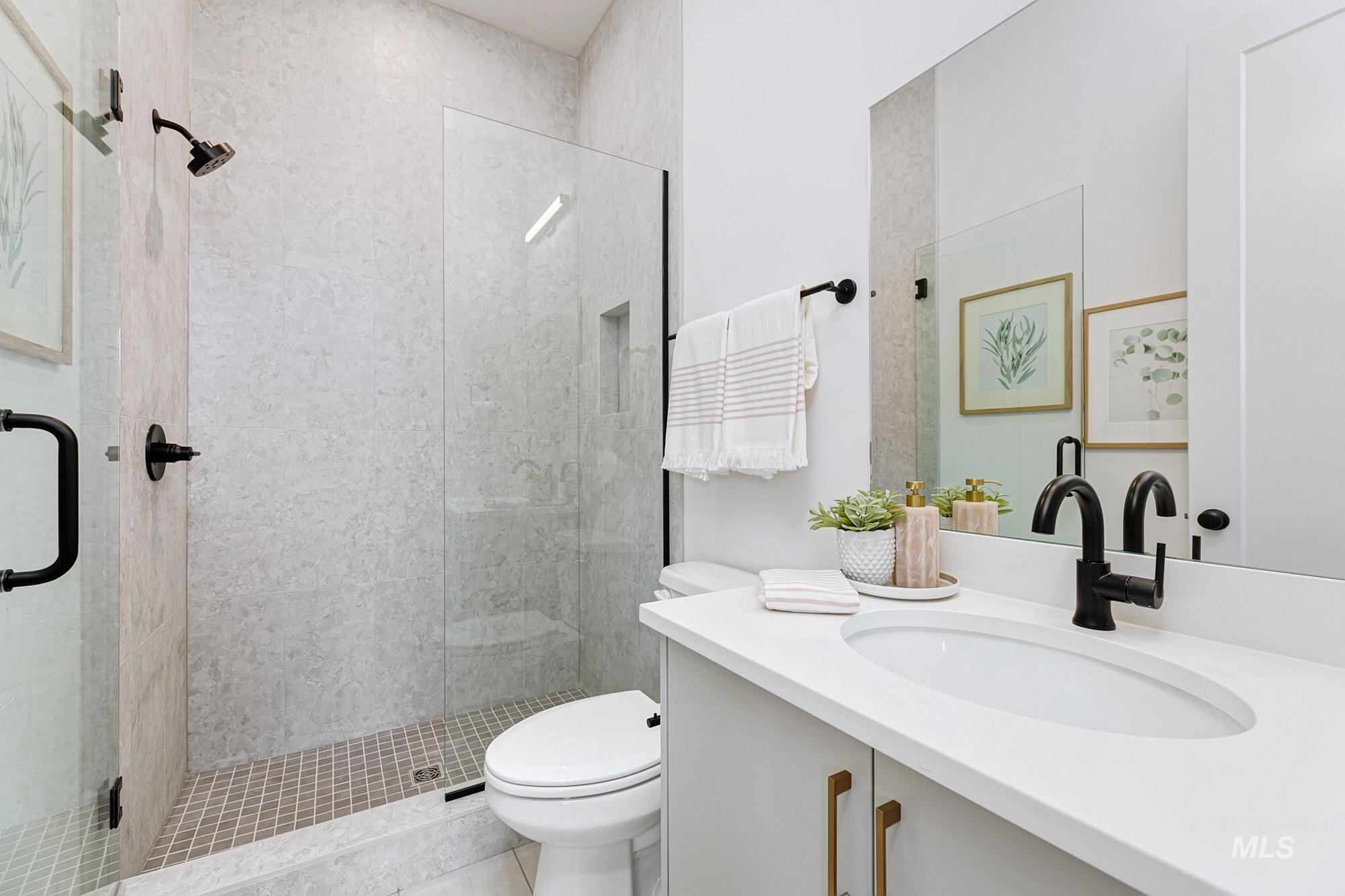 Contemporary bathroom featuring a frameless glass shower enclosure, a shower niche, and a matte black shower head