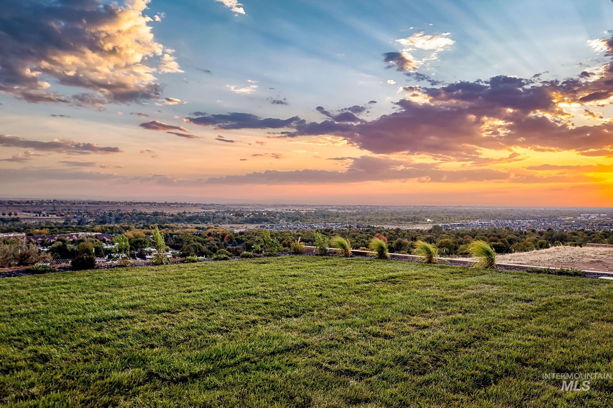 Expansive green lawn with a low stone retaining wall and distant city and horizon scenery