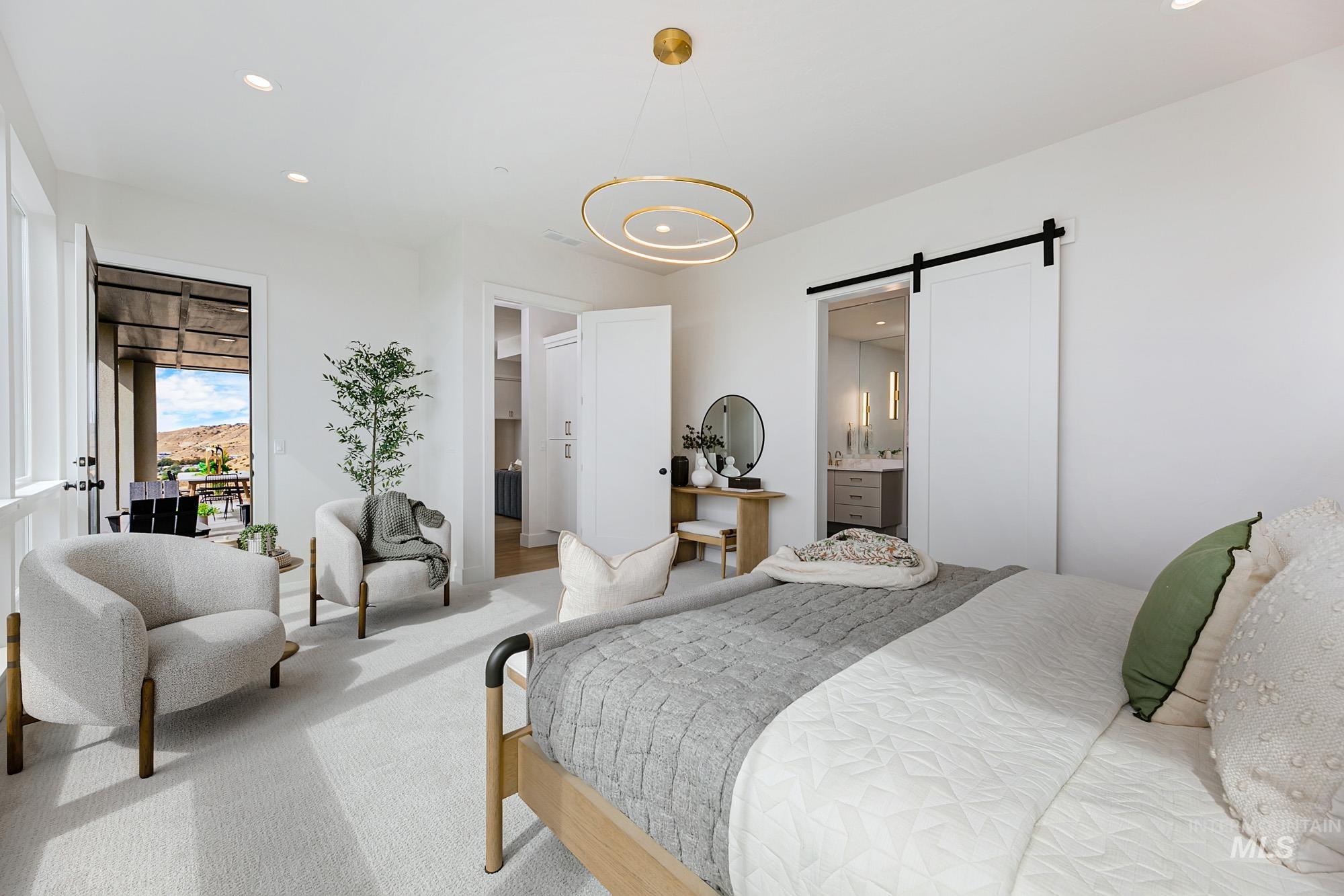 Spacious room featuring light-toned carpeting, a contemporary gold-toned circular chandelier, recessed lighting, and a white barn door
