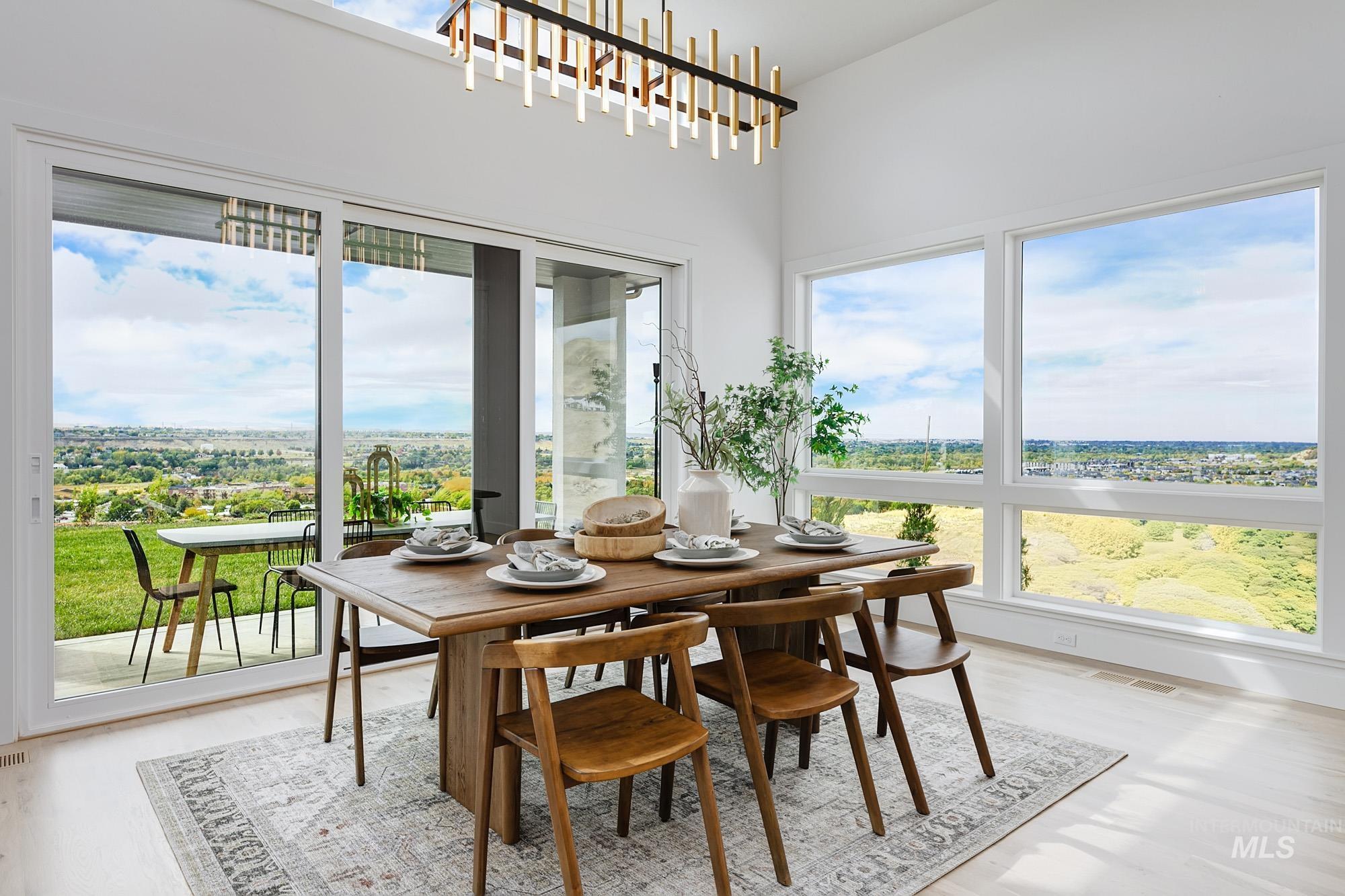 Dining space featuring expansive windows and sliding glass doors, a high ceiling, and wood-finish flooring