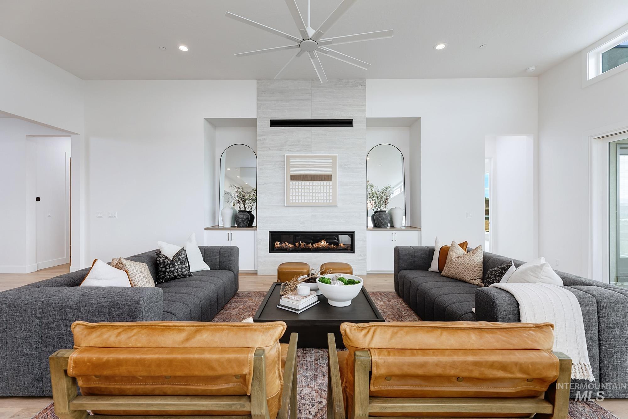 Spacious living area featuring a modern linear fireplace with a stone-finish facade, flanked by arched alcoves with built-in cabinetry