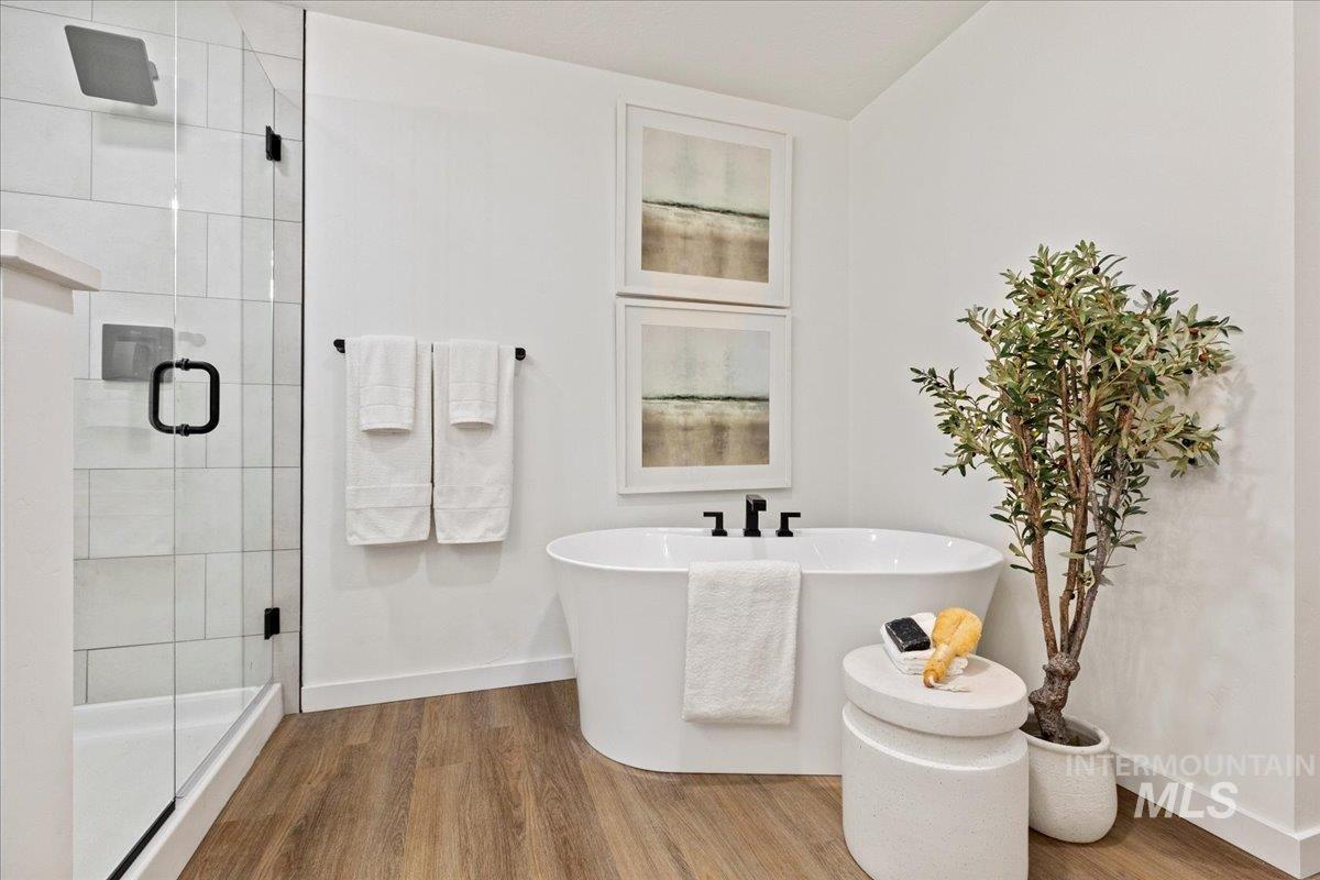 Full bathroom with a shower stall, wood finished floors, and a freestanding bath