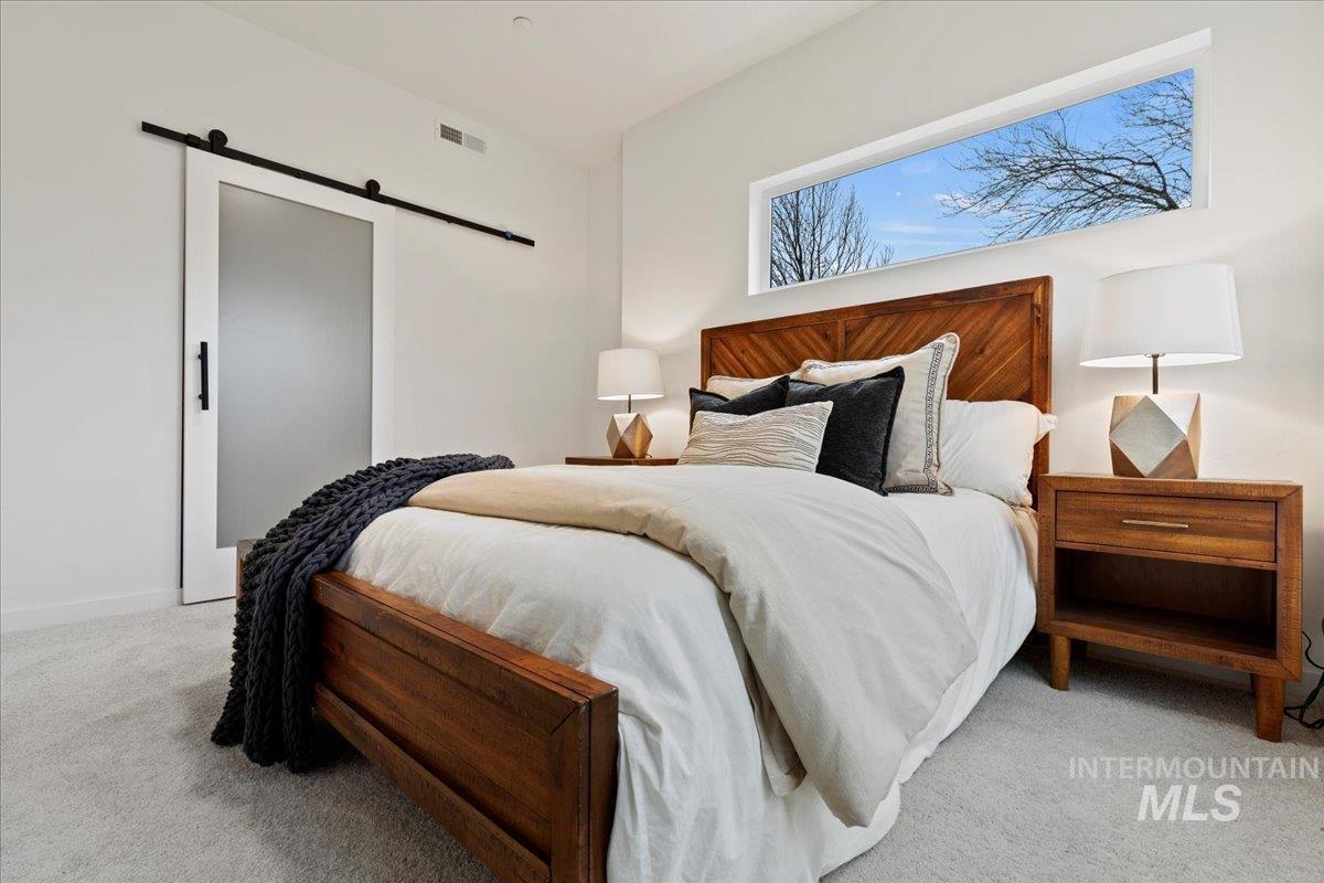Bedroom with a barn door and light colored carpet