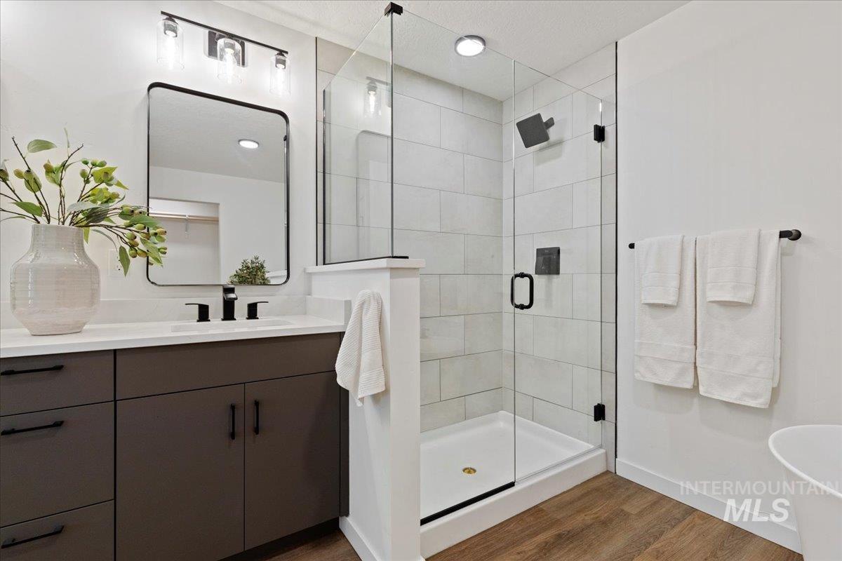 Bathroom featuring a stall shower, vanity, dark wood finished floors, recessed lighting, and a soaking tub