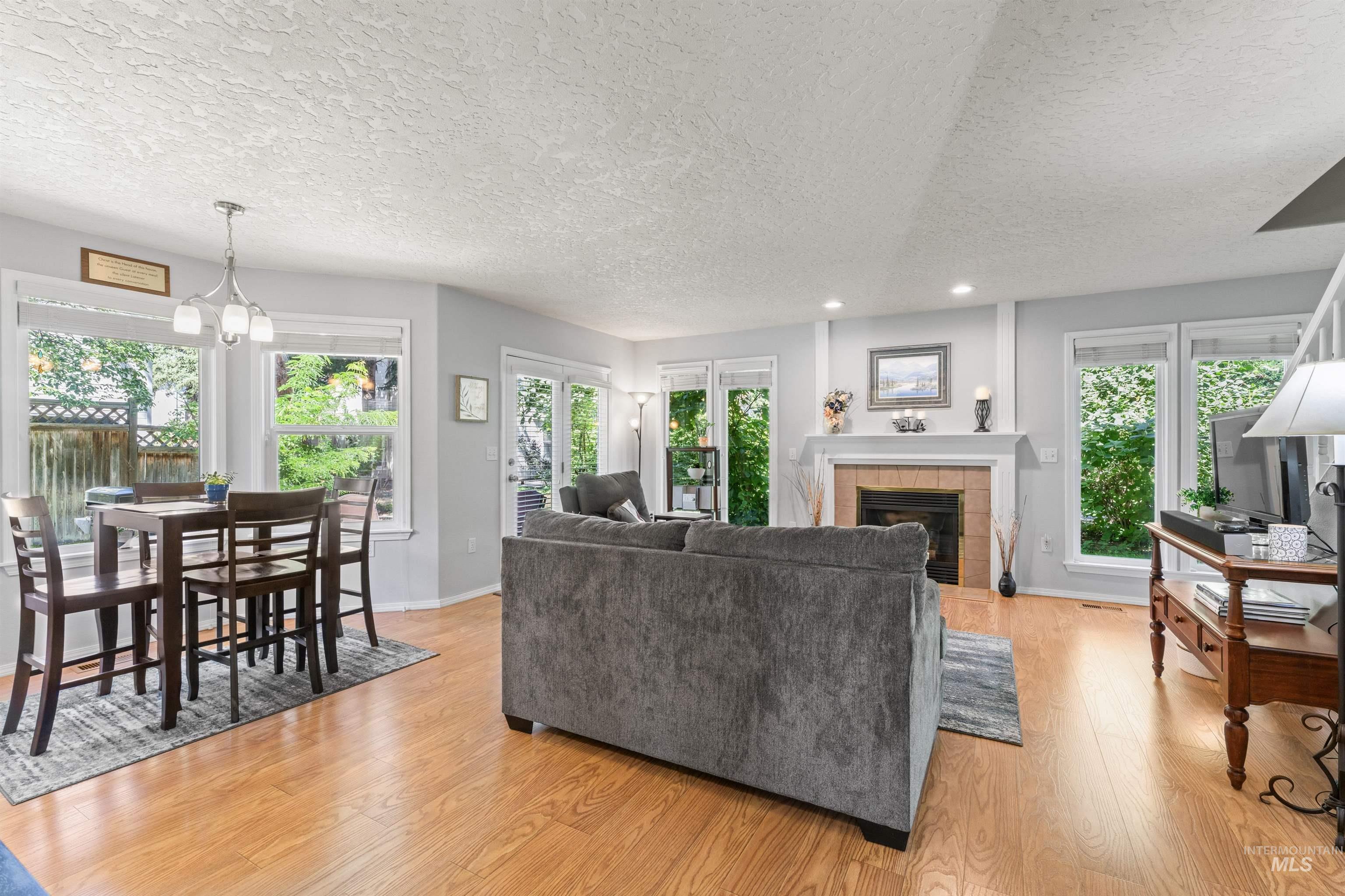 Living area featuring a textured ceiling, light wood finished floors, recessed lighting, a tile fireplace, and a chandelier