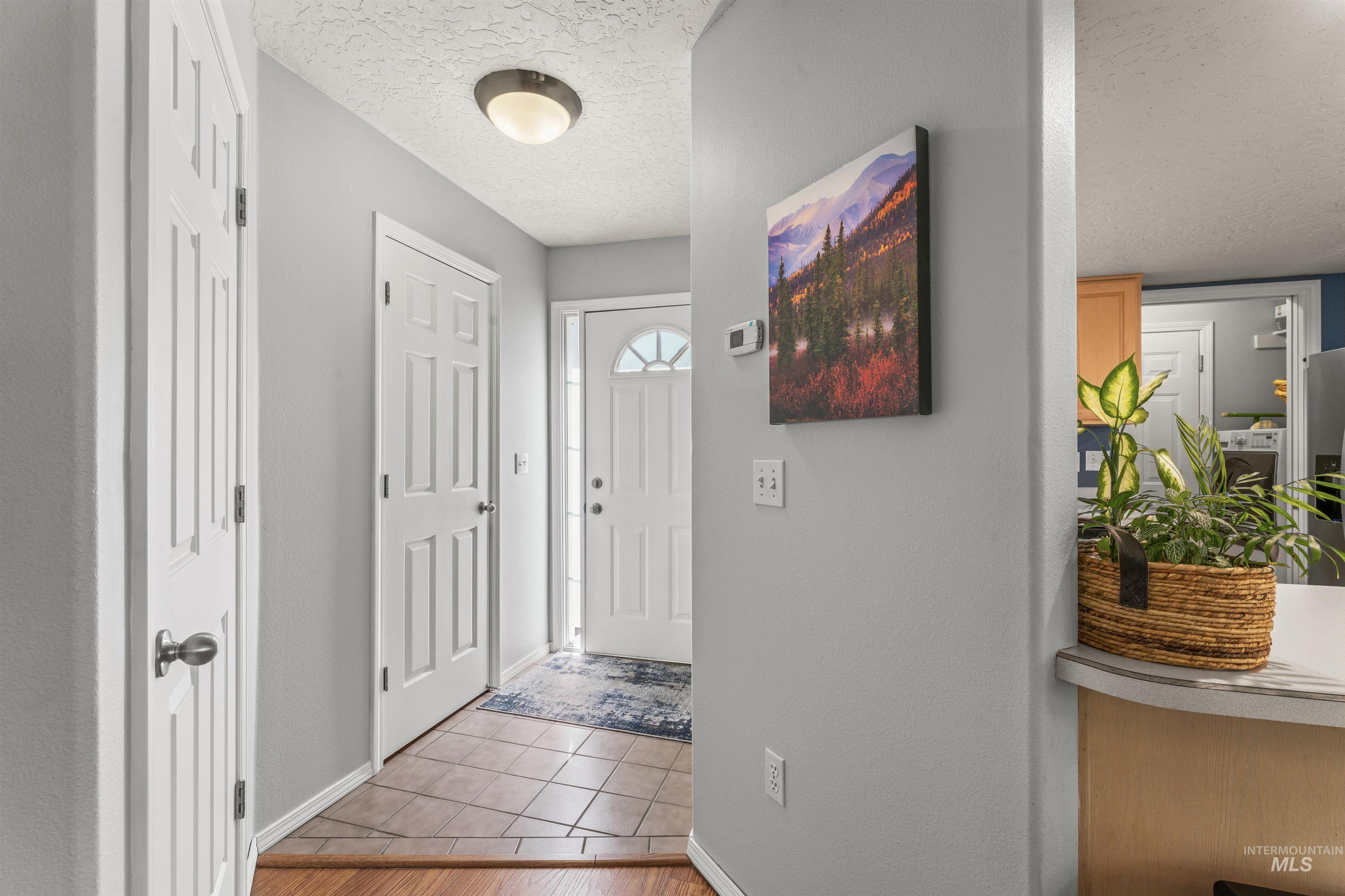 Tiled foyer featuring a textured ceiling and washer / dryer