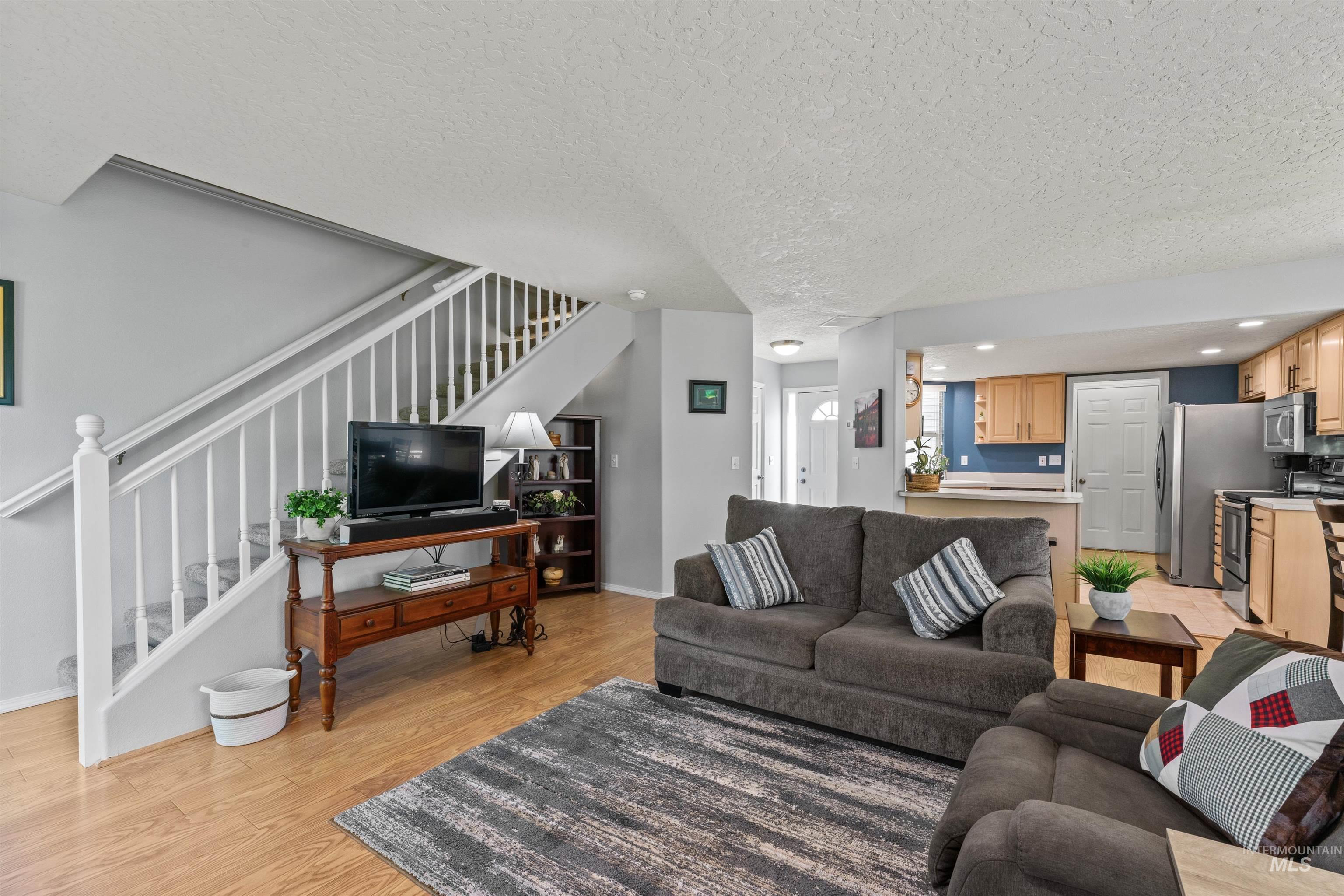 Living area with stairs, light wood-style floors, a textured ceiling, and recessed lighting