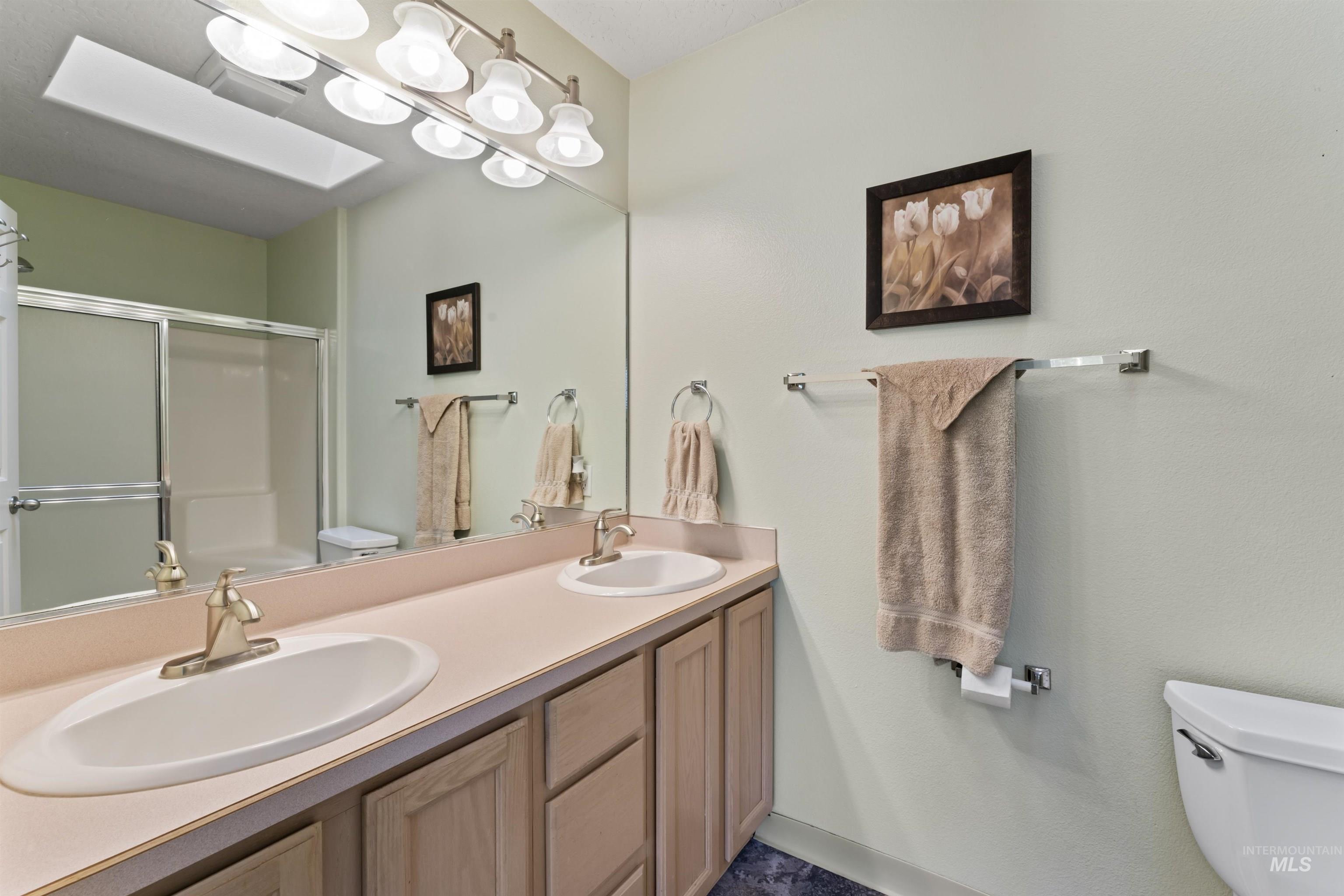 Full bath with a shower with shower door and double vanity