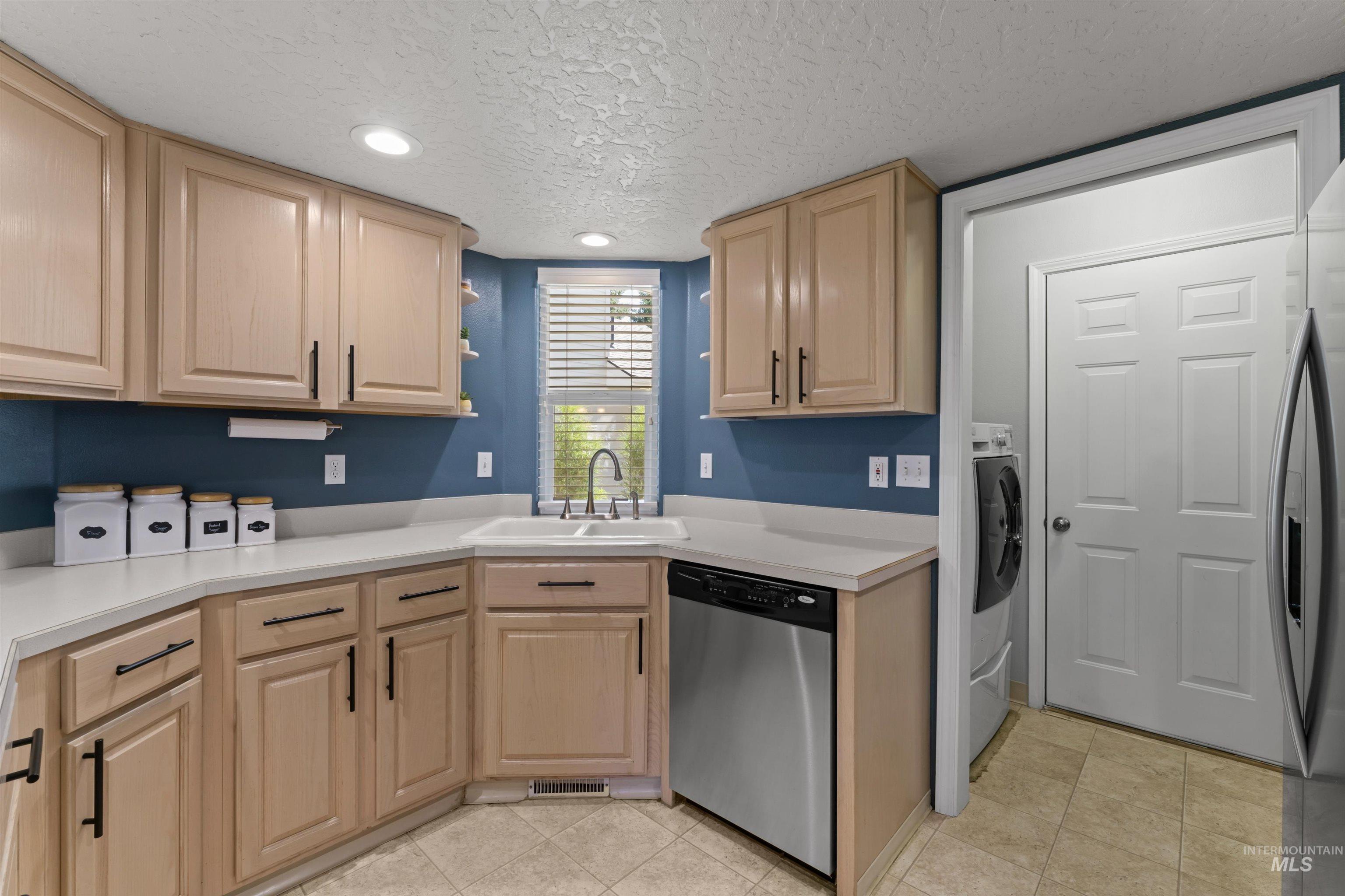 Kitchen with stainless steel appliances, light brown cabinetry, light countertops, a textured ceiling, and recessed lighting
