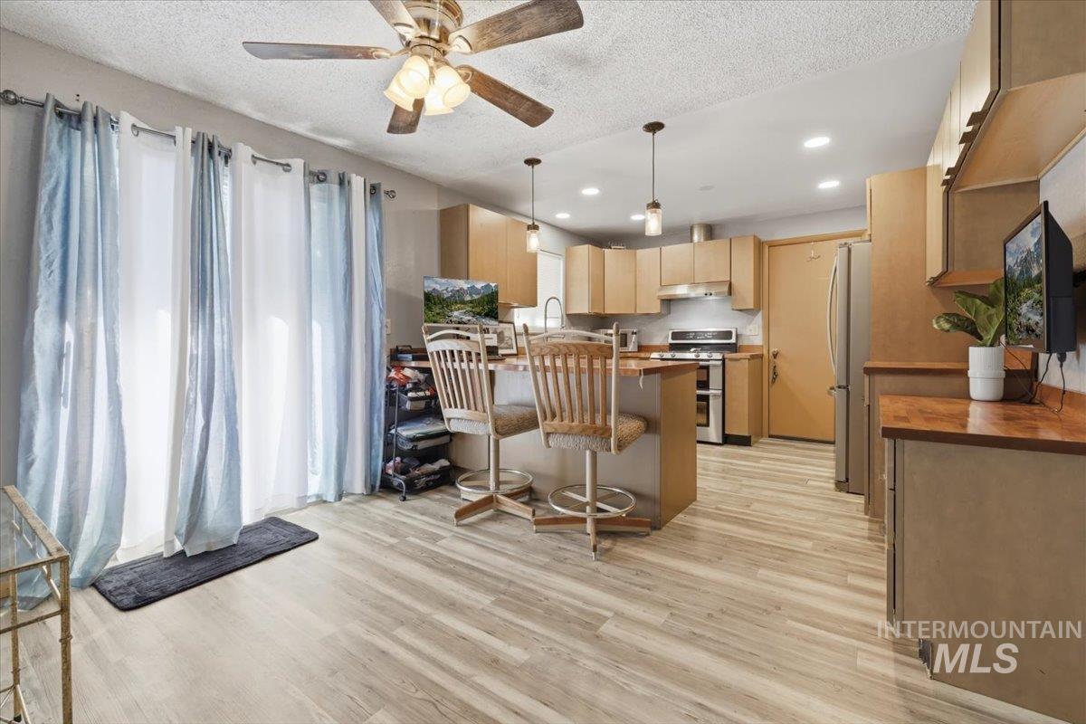 Open-concept kitchen and dining area featuring wood-finish flooring, recessed lighting, and a ceiling fan