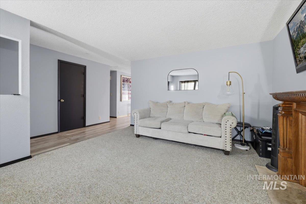 Spacious living area featuring light gray walls and a textured ceiling