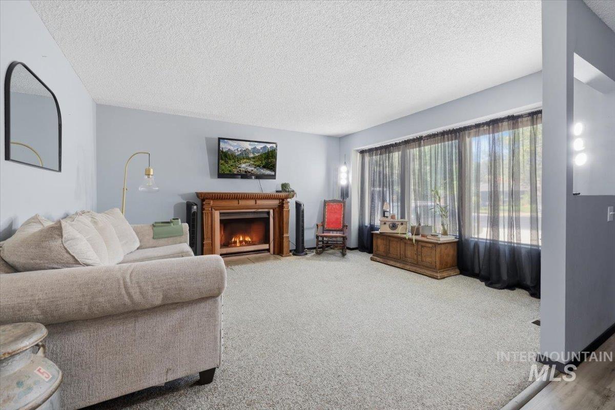 Living area featuring a traditional wood mantel fireplace and large front-facing windows