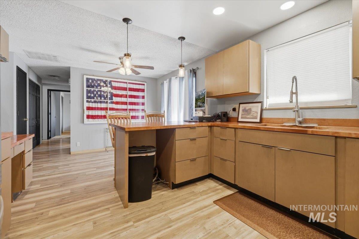 Modern kitchen featuring wood-finish flooring, light wood cabinetry, and a wood countertop