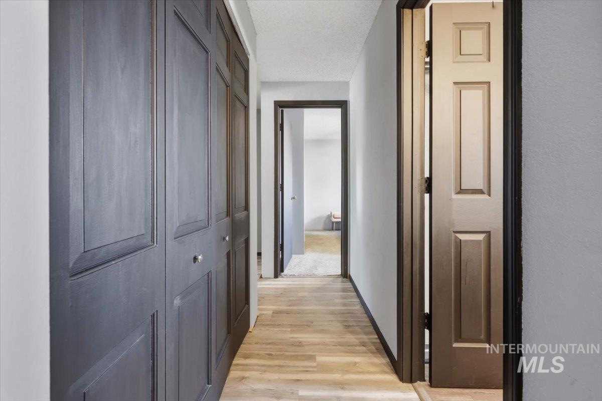 Hallway with wood-finish flooring, paneled doors, and a neutral color palette