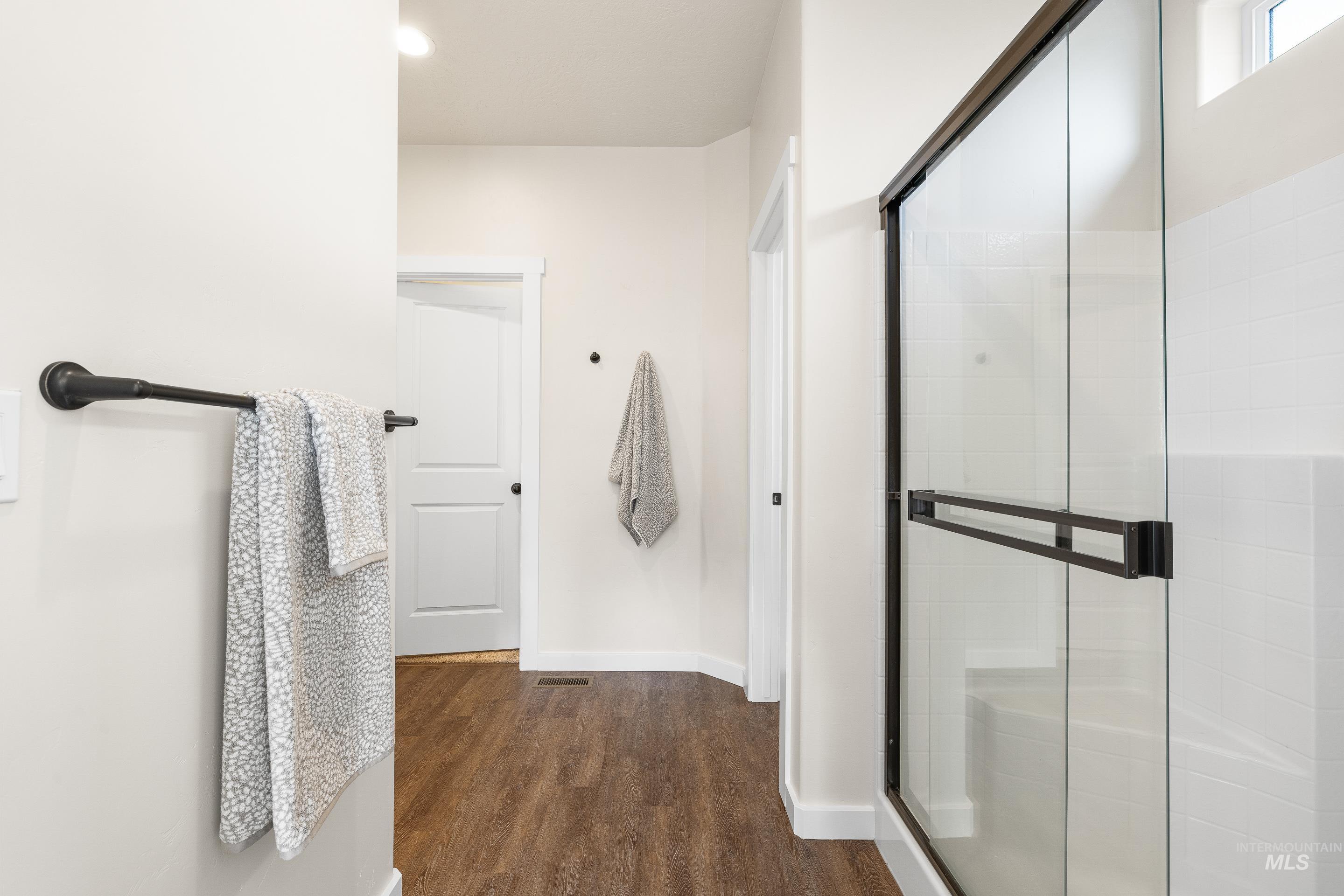 Full bath featuring dark wood-style floors and a stall shower