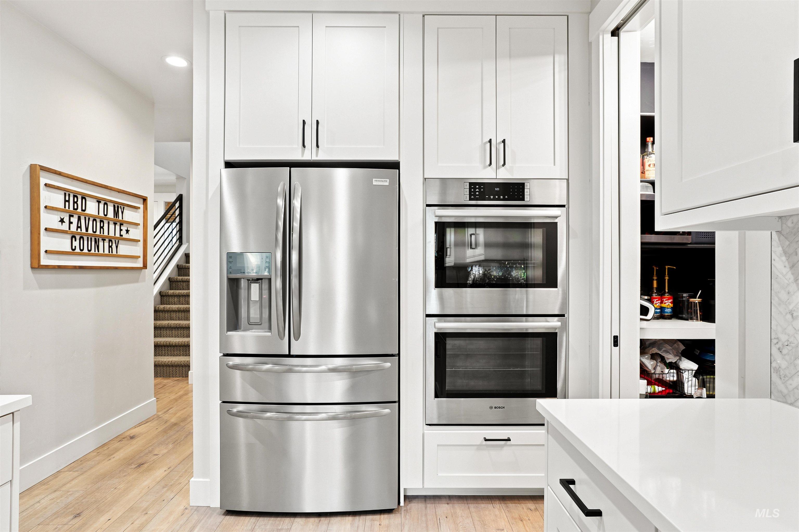 Contemporary kitchen featuring white cabinetry, stainless steel appliances, integrated double ovens, and a built-in refrigerator