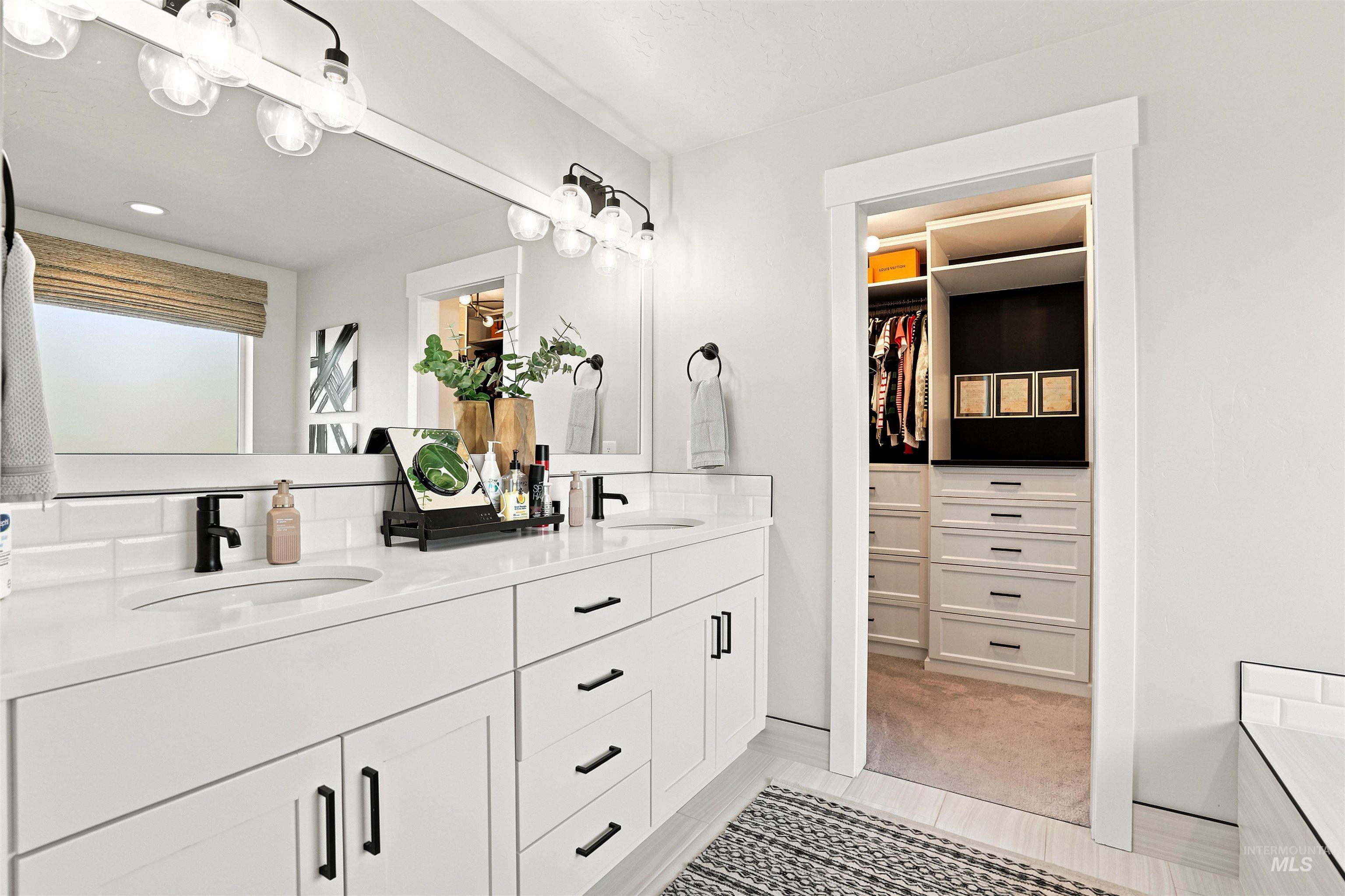 Bathroom featuring a dual vanity with white cabinetry, white countertops, and matte black fixtures