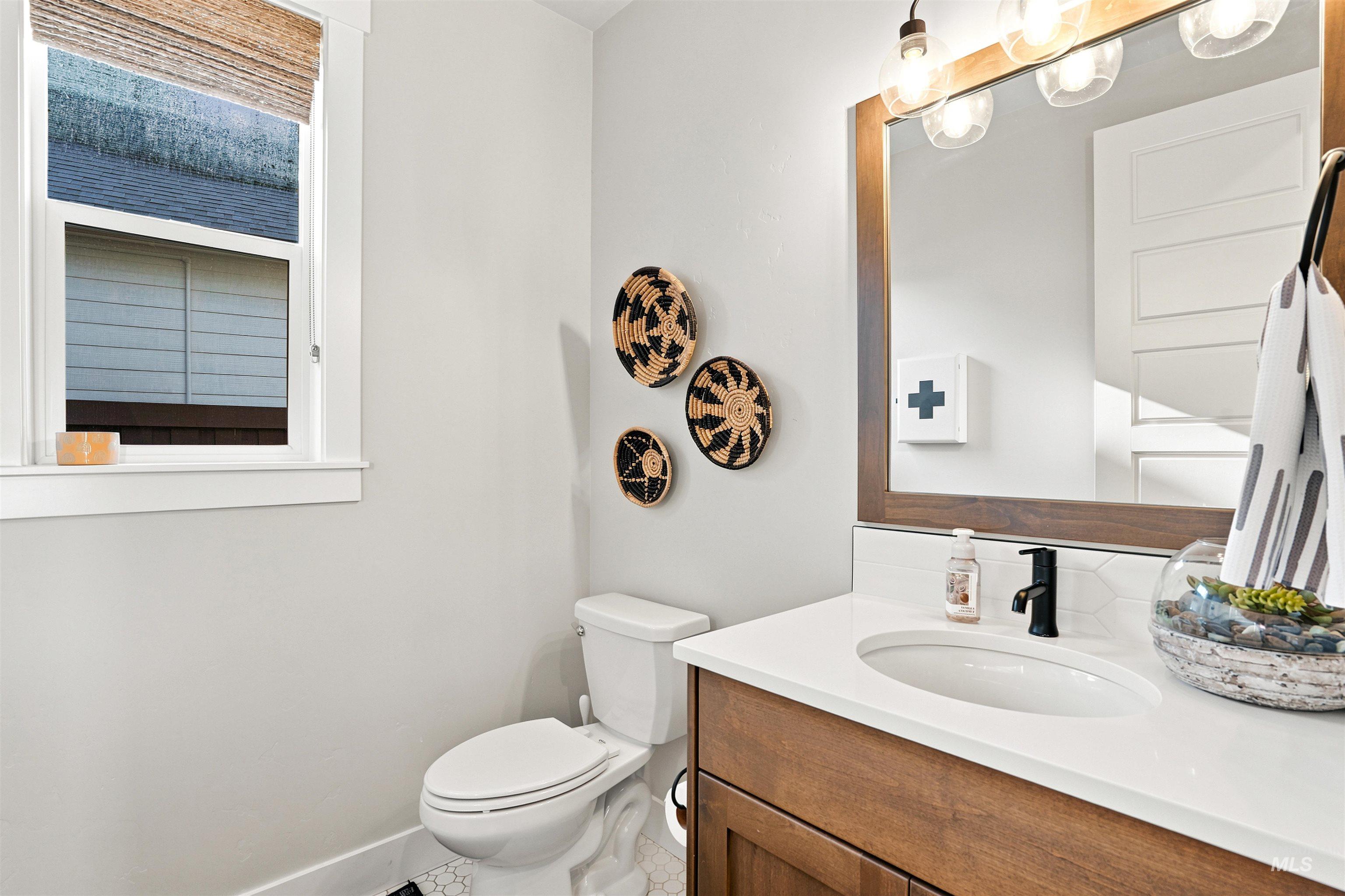 Vanity with wood-finish cabinetry, white countertop, and integrated sink