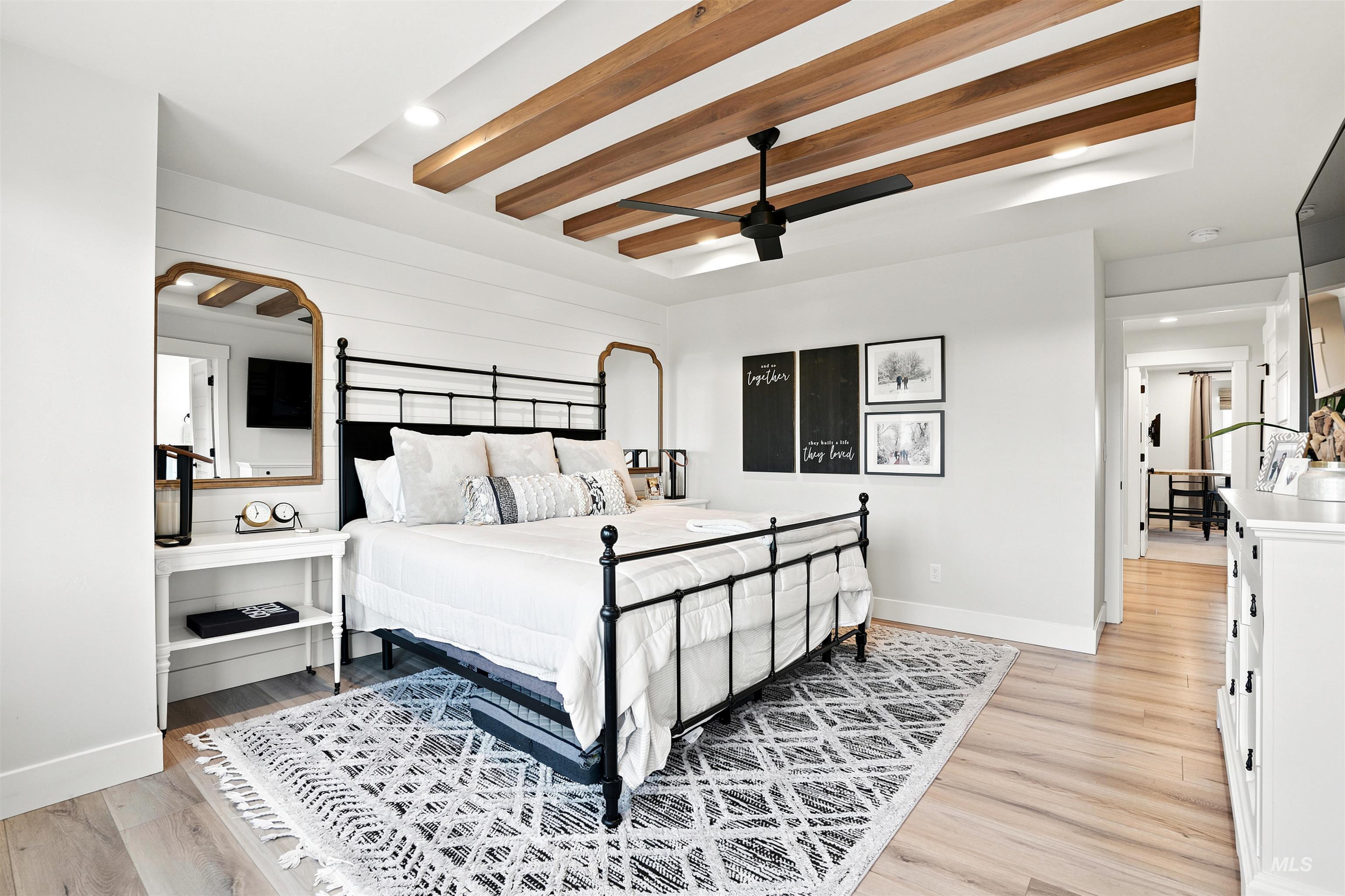 Recessed ceiling with wood-finish beams and a black ceiling fan
