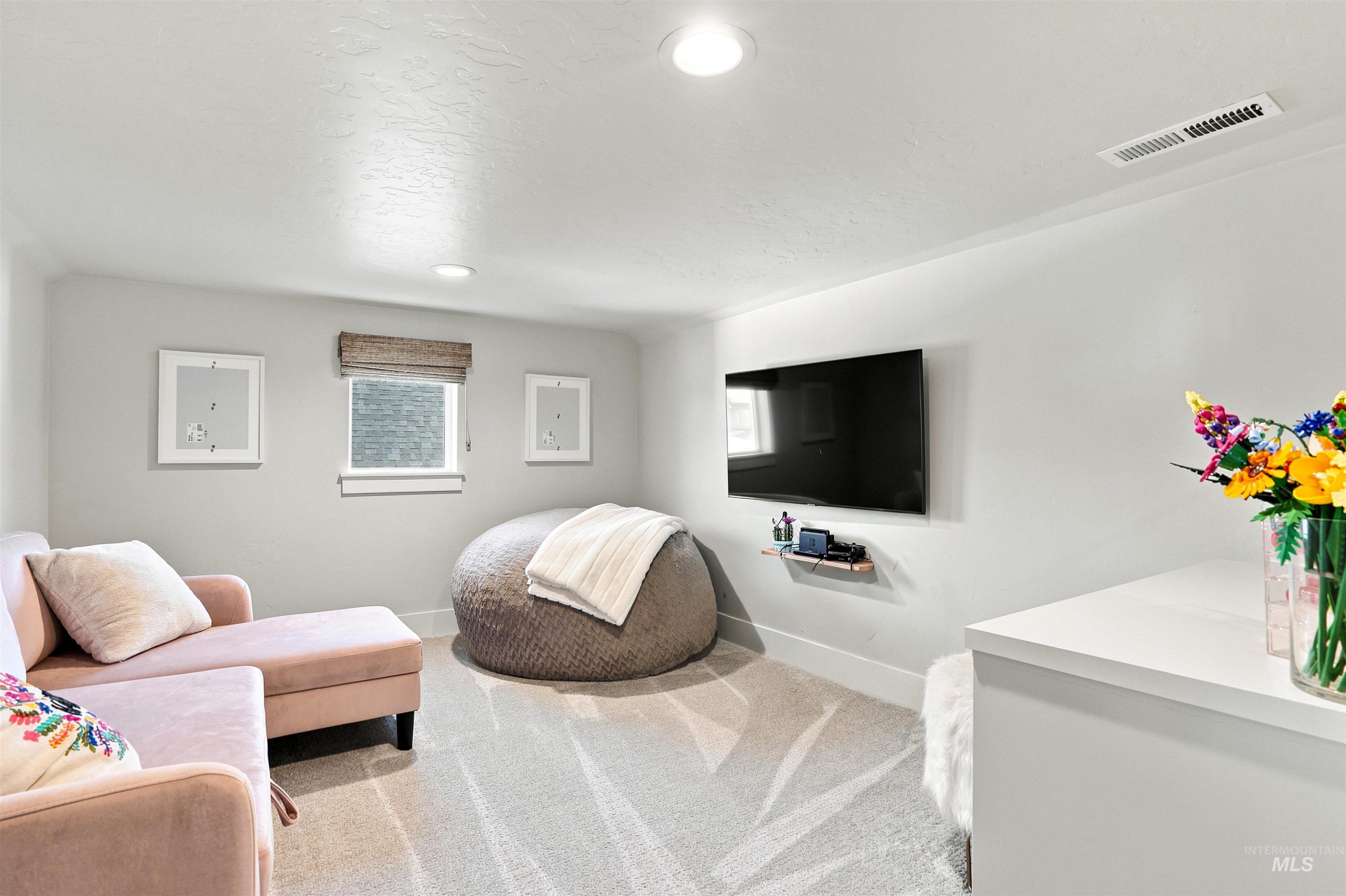 Neutral-toned room featuring a single window with a woven Roman shade, recessed lighting, and light-colored patterned carpeting