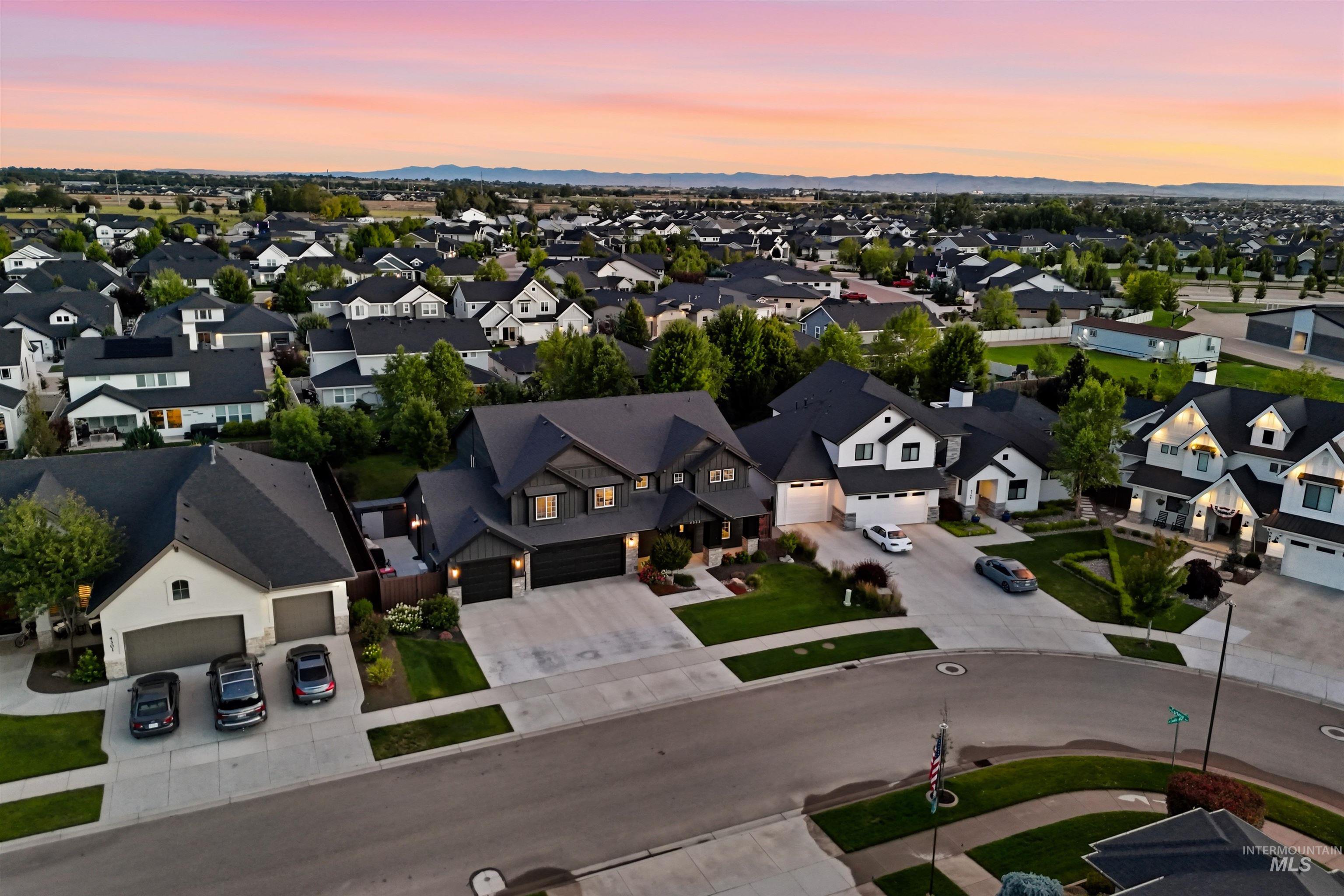 Residential neighborhood featuring an array of homes with dark shingle roofs, well-maintained green lawns, and paved driveways