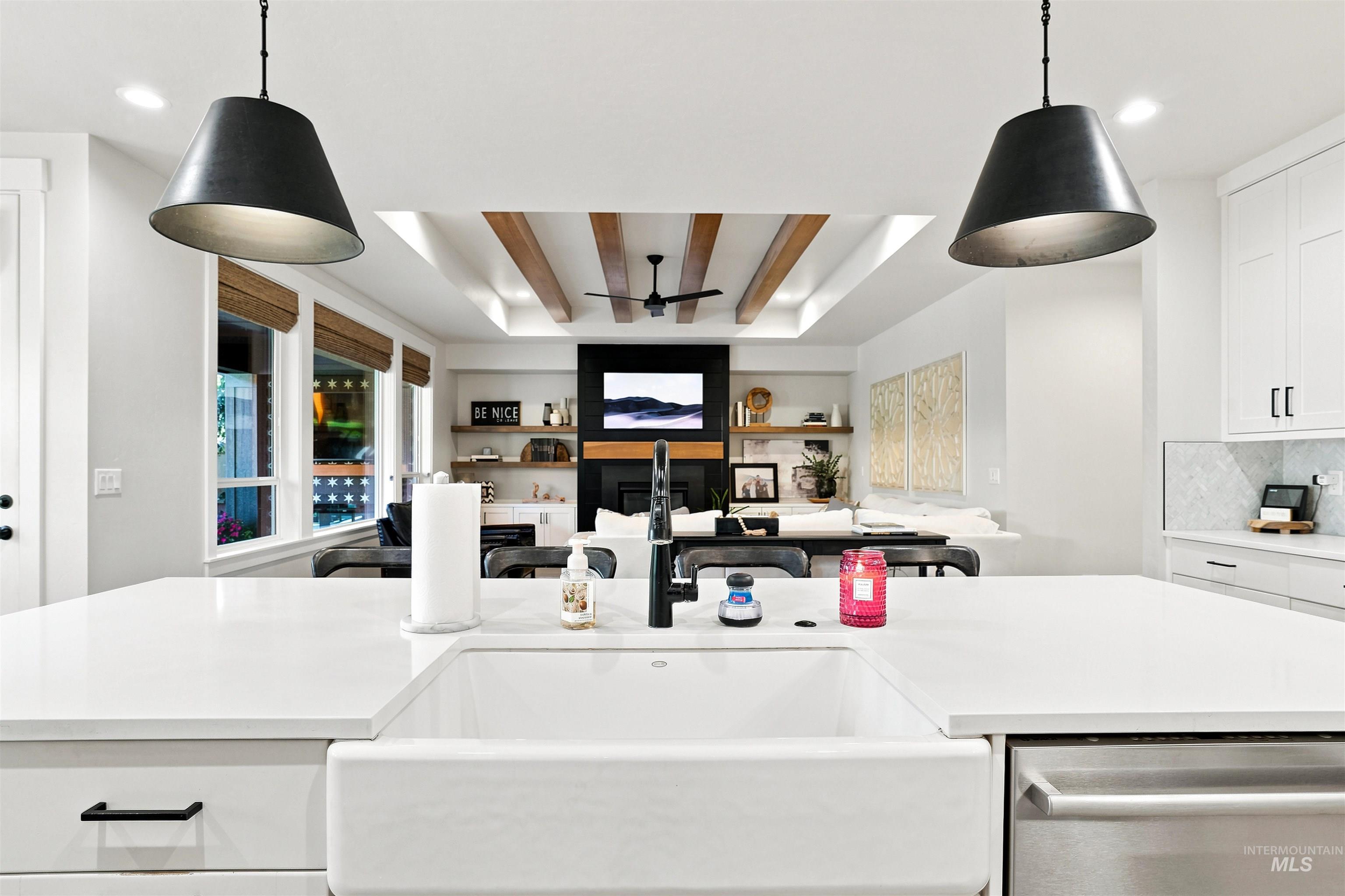 Kitchen island with a white farmhouse sink, modern pendant lighting, and stainless steel dishwasher