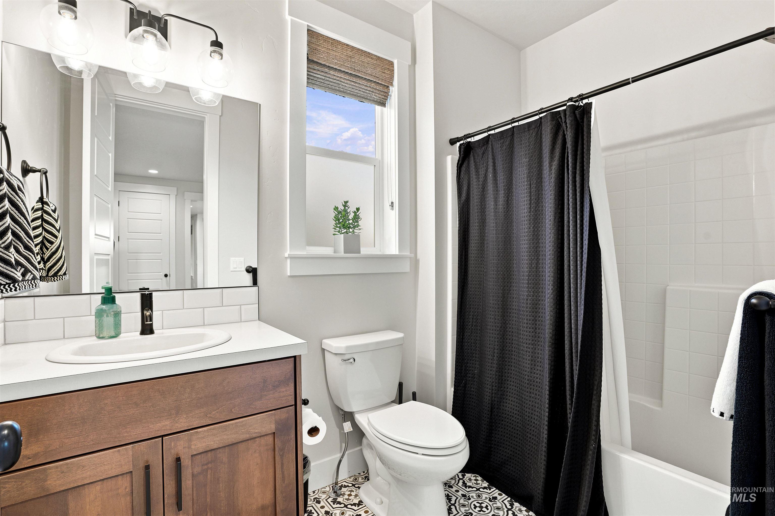 Bathroom featuring a wood vanity with a white countertop, subway tile backsplash, and an undermount sink