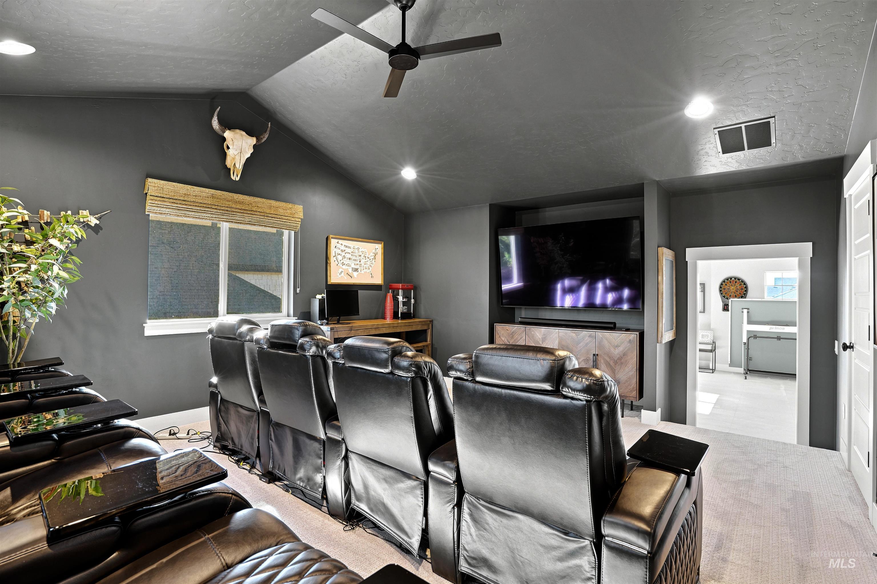 Dedicated media room with vaulted ceilings, recessed lighting, a modern ceiling fan, and a built-in entertainment center